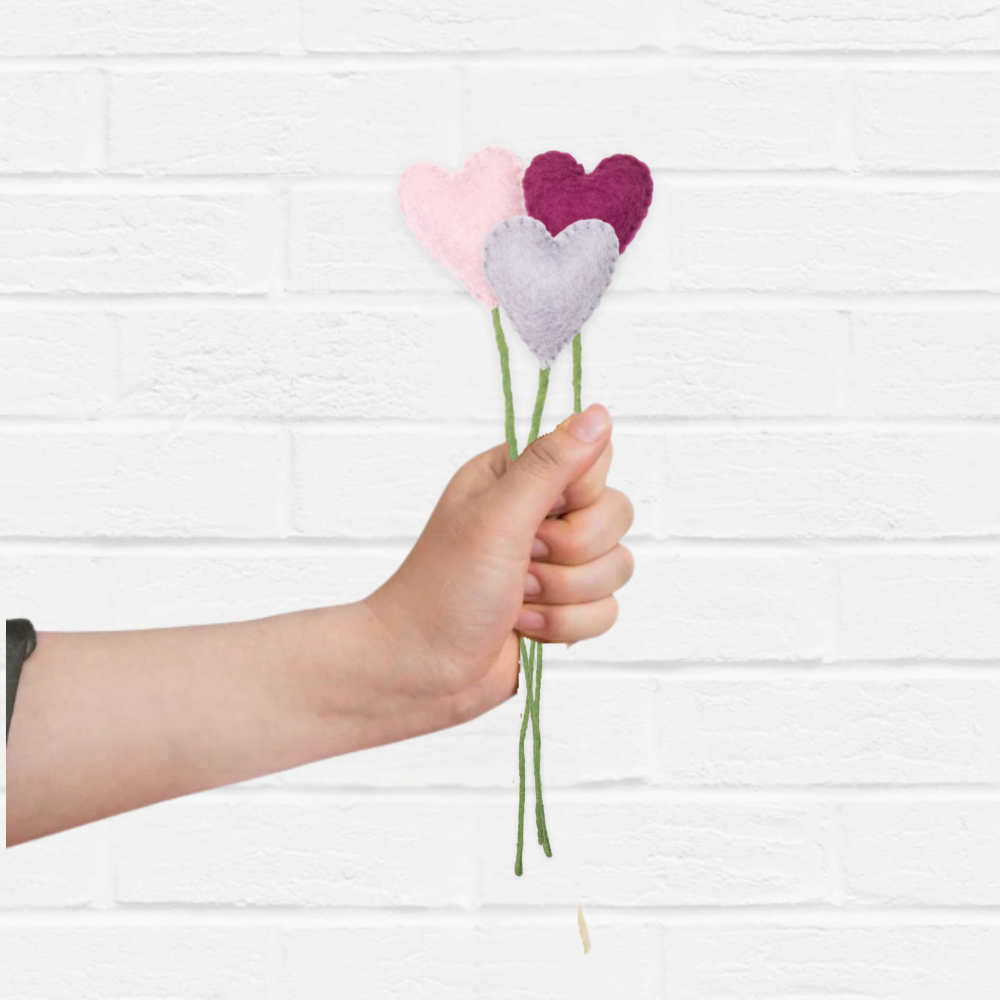 Hand holding a bouquet of heart-shaped flowers against a white background