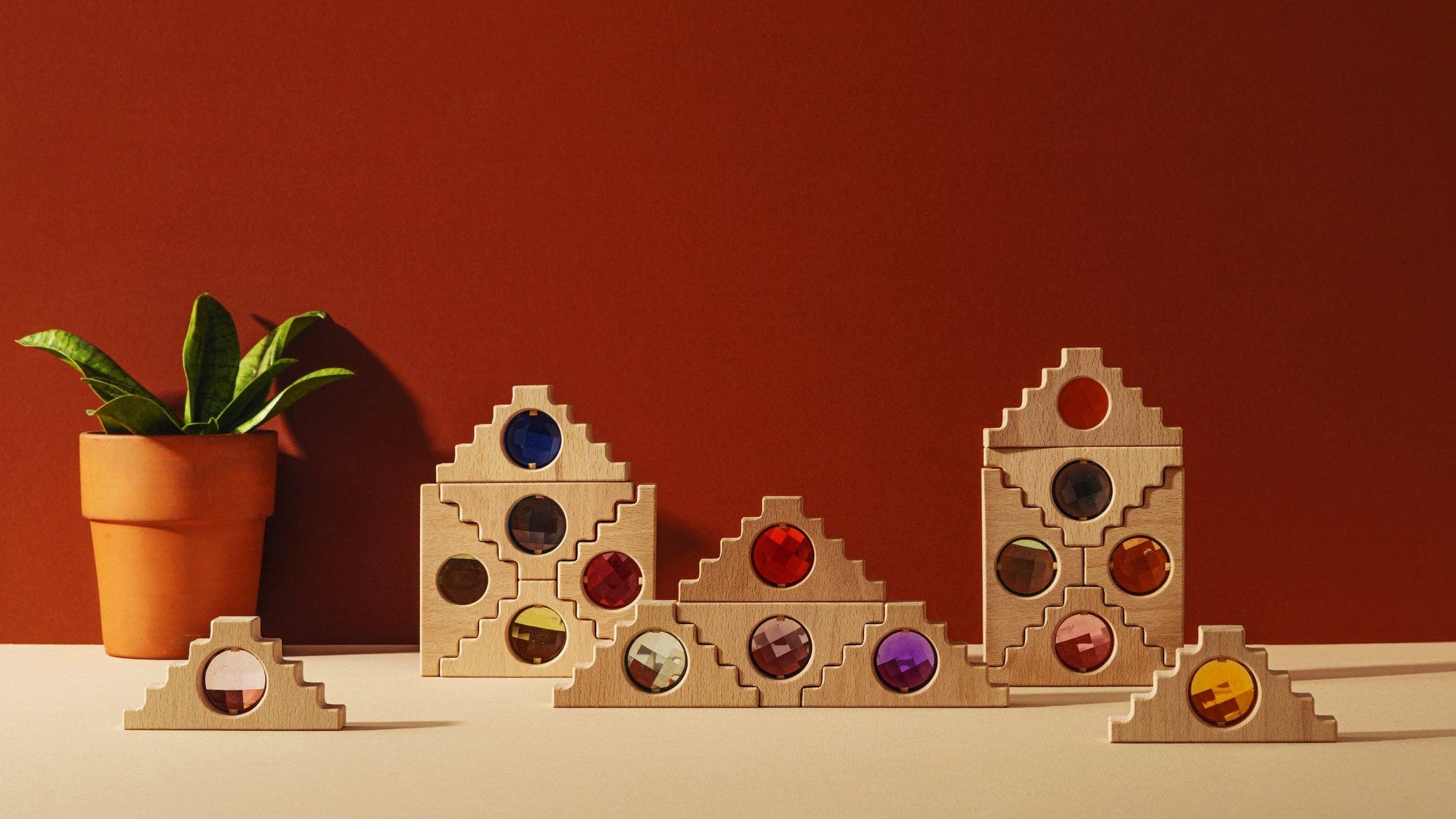 Set of wooden geometric shapes with colored gems on a red background