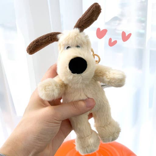 Plush dog toy held by a hand with a soft white background