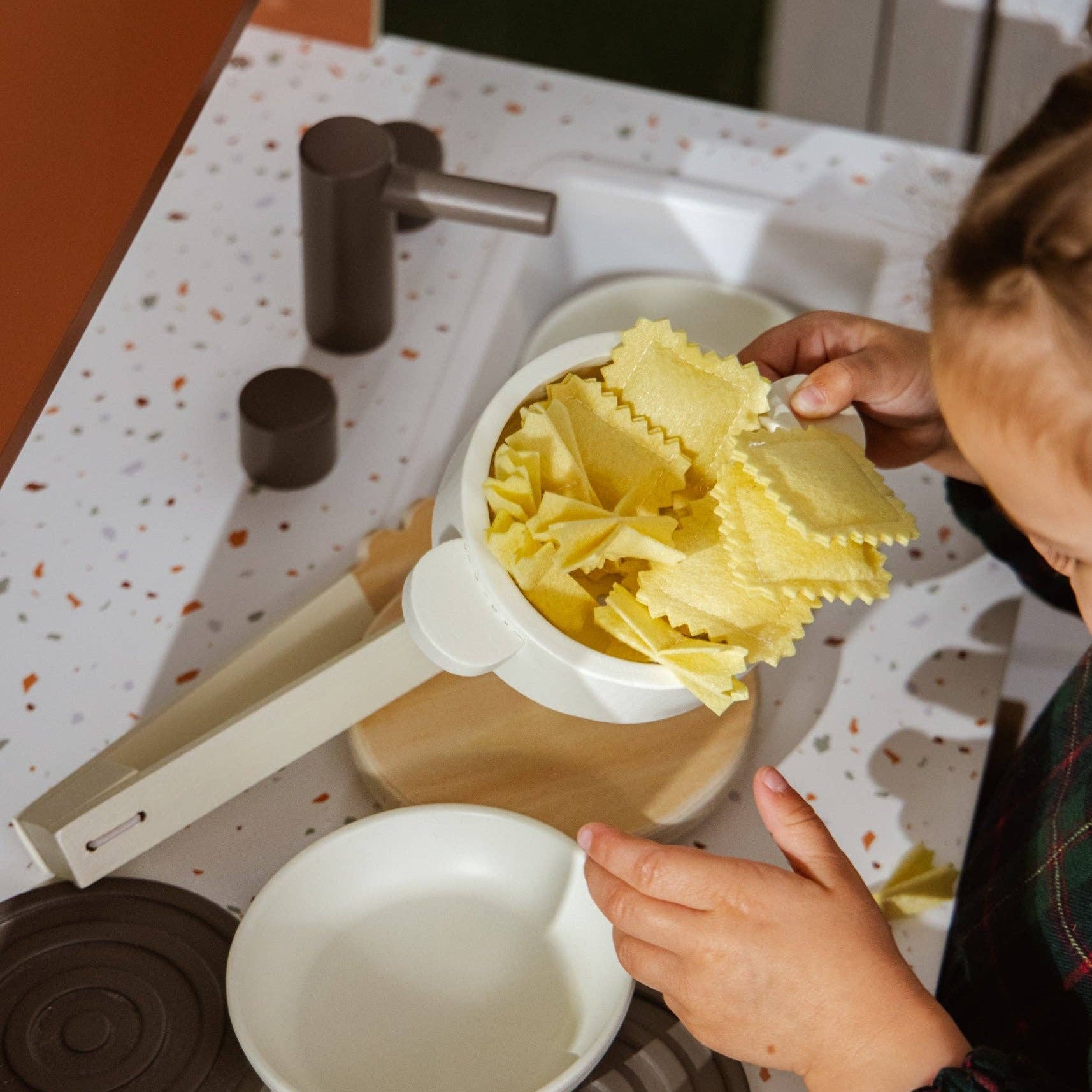 Person preparing pasta in a kitchen setting with a focus on the hands and the pasta-making process.