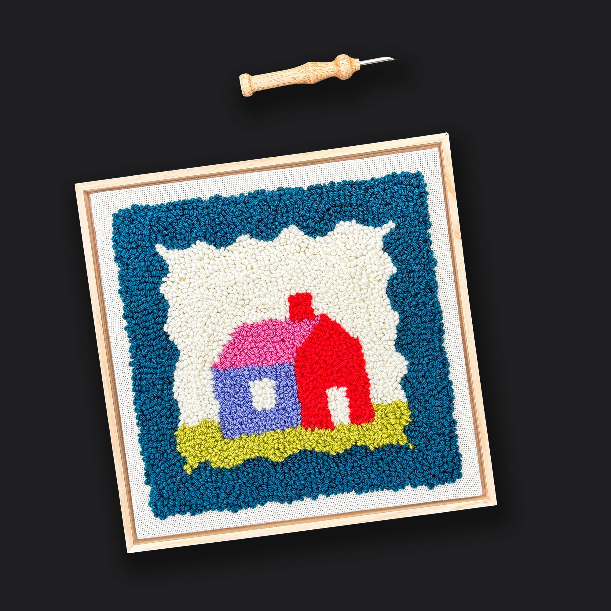 Colorful woven artwork of a house with a wooden frame on a black background