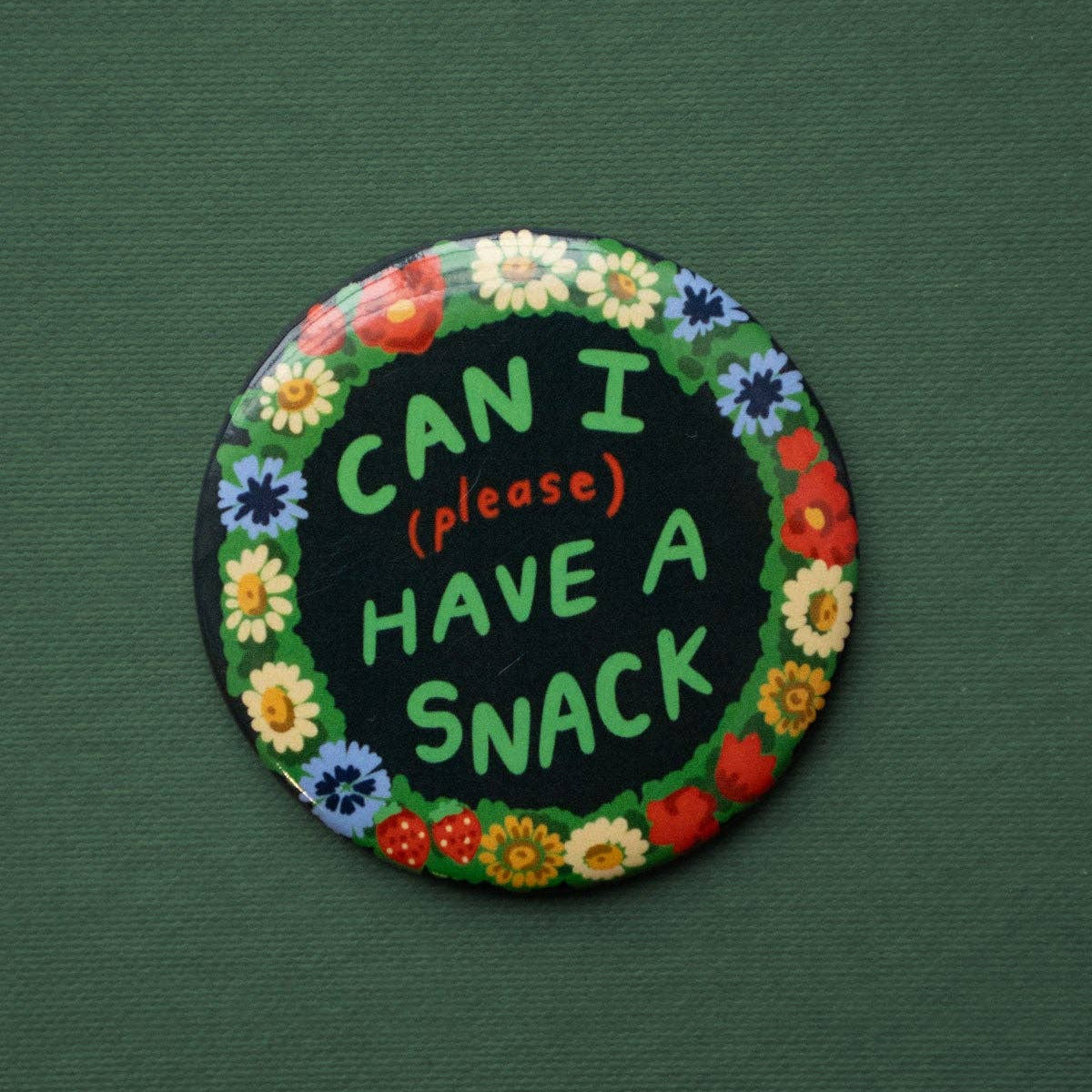 Circular patch with floral border and text 'Can I (please) have a snack' on a green background