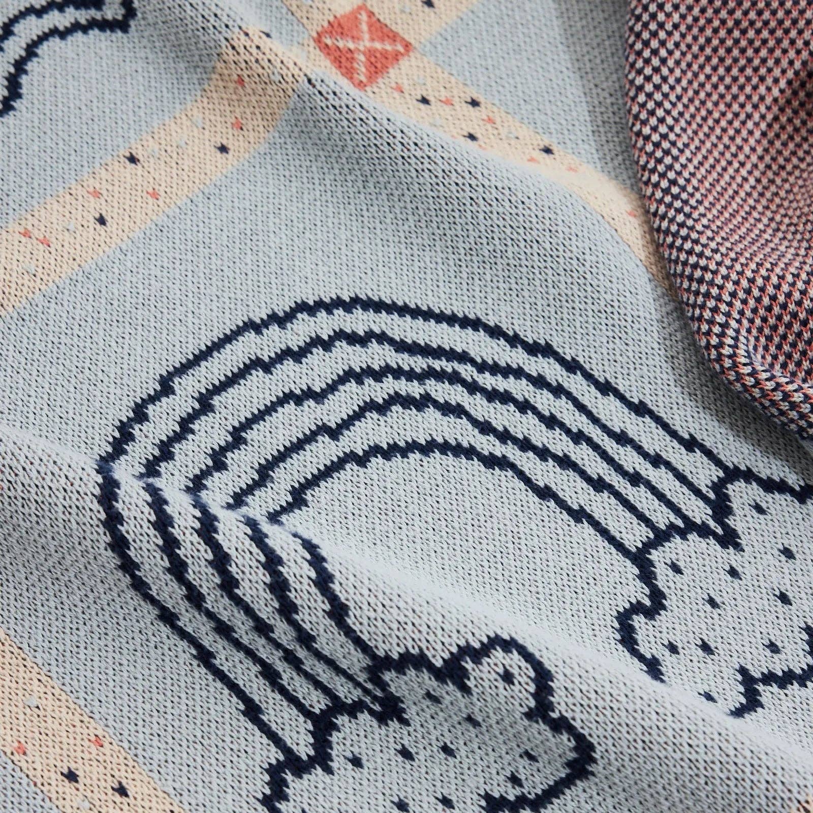 Textile with a rainbow and cloud design on a light blue background