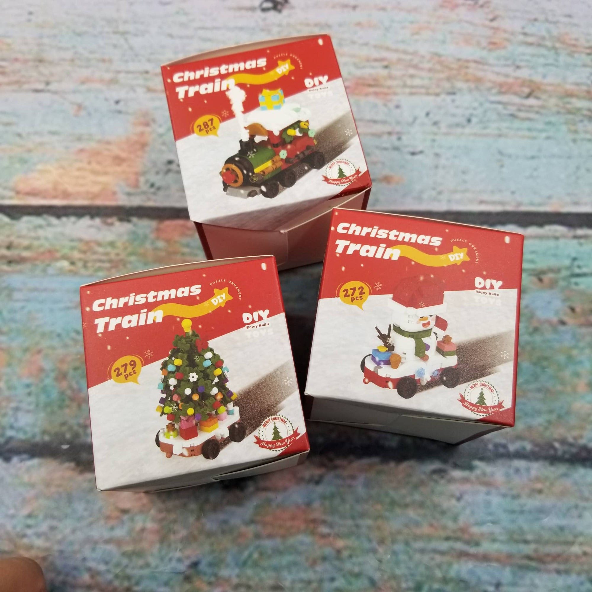 Three boxes of Christmas Train DIY sets on a textured surface