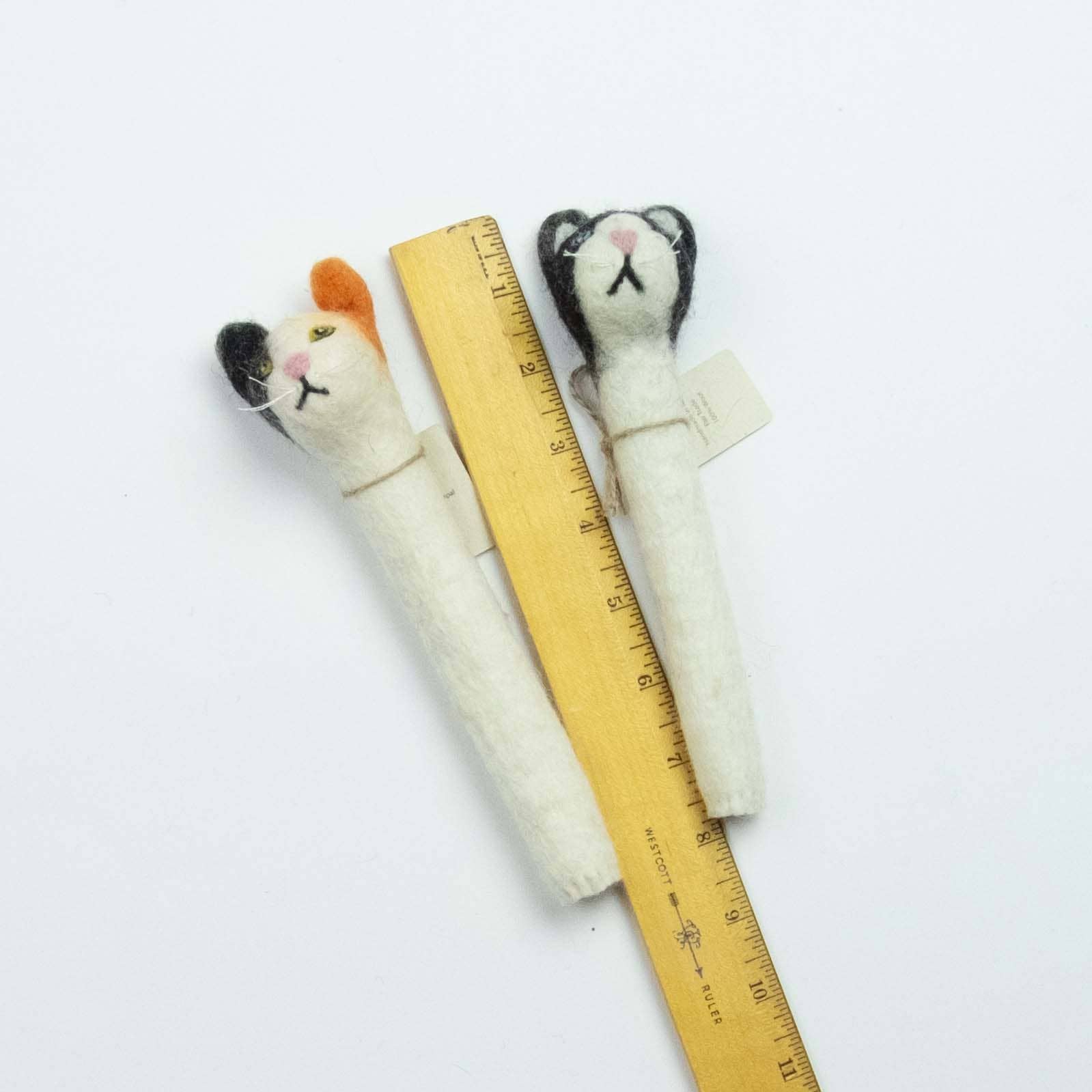 Two felted cat toys with a ruler for scale on a white background
