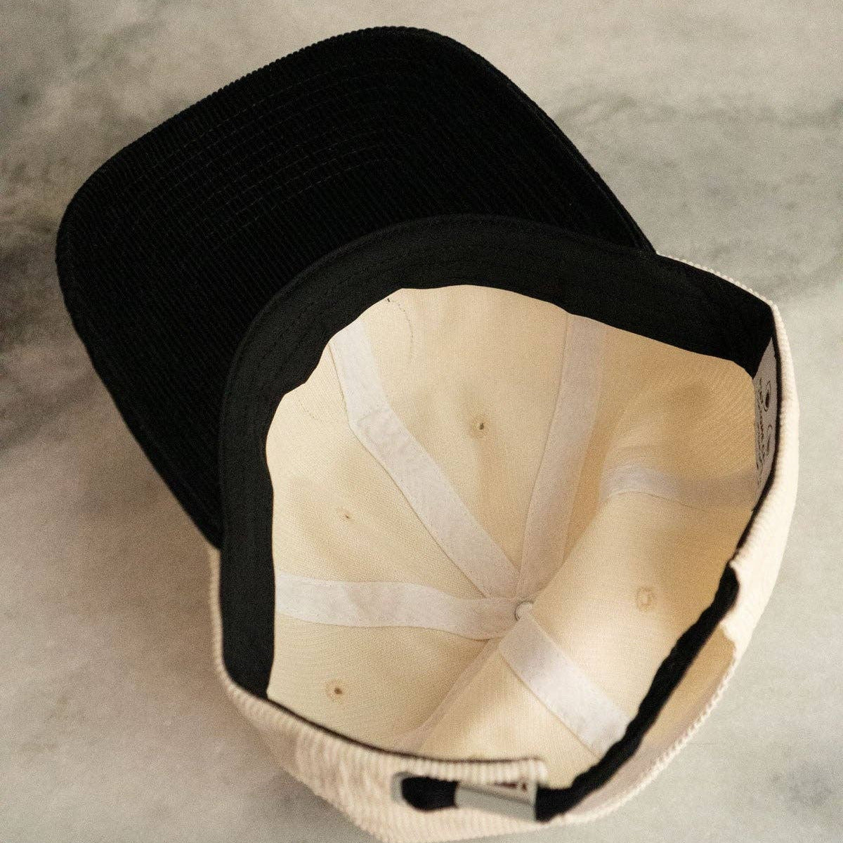 Black cap with beige interior on a gray surface