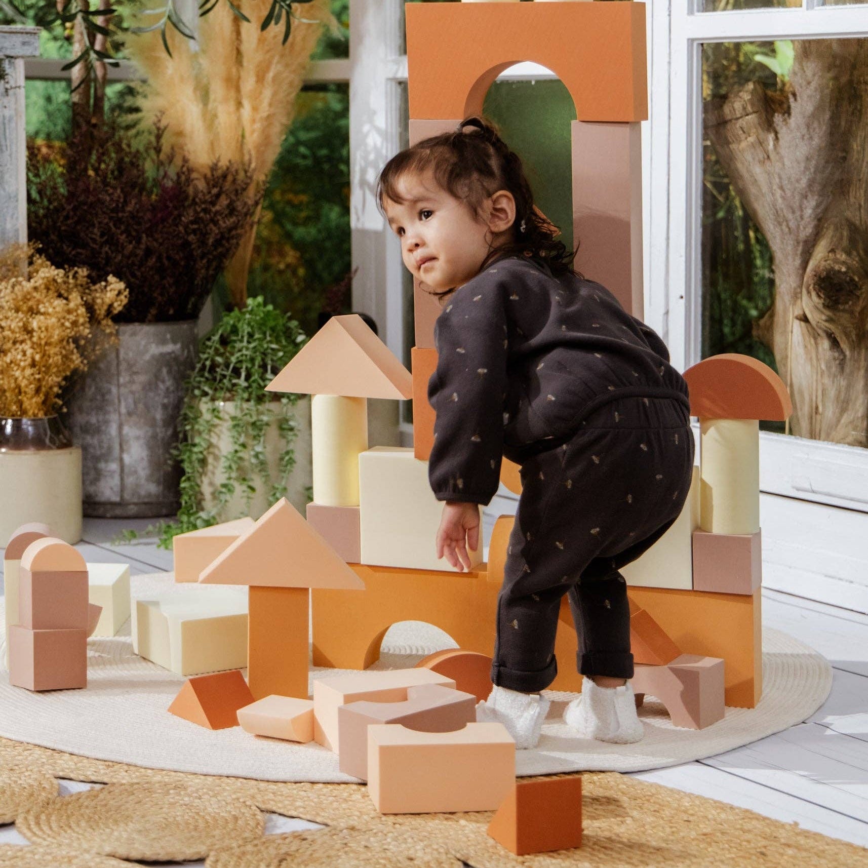 Child playing with wooden blocks in a garden setting