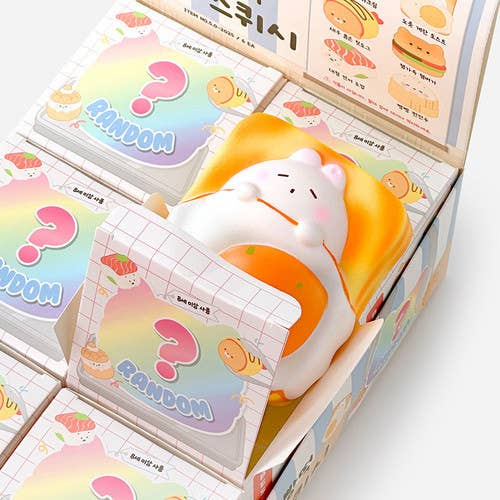 Squishy toy with a white cat design on top of a box labeled 'Random' with colorful packaging.