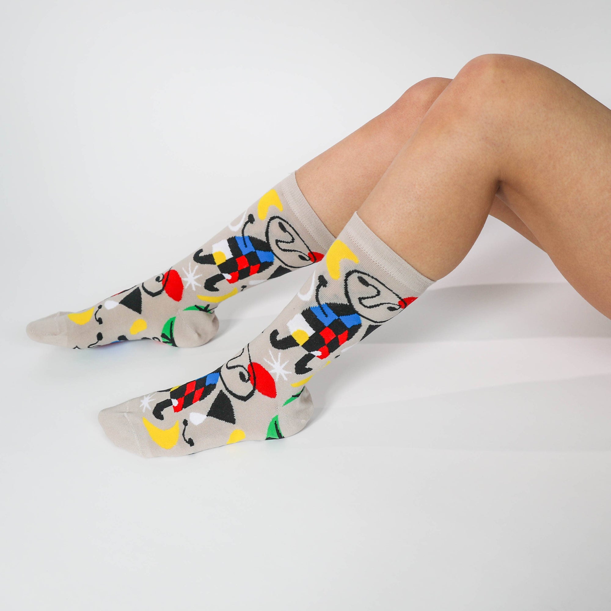 Colorful socks with abstract designs worn by a person on a light gray background