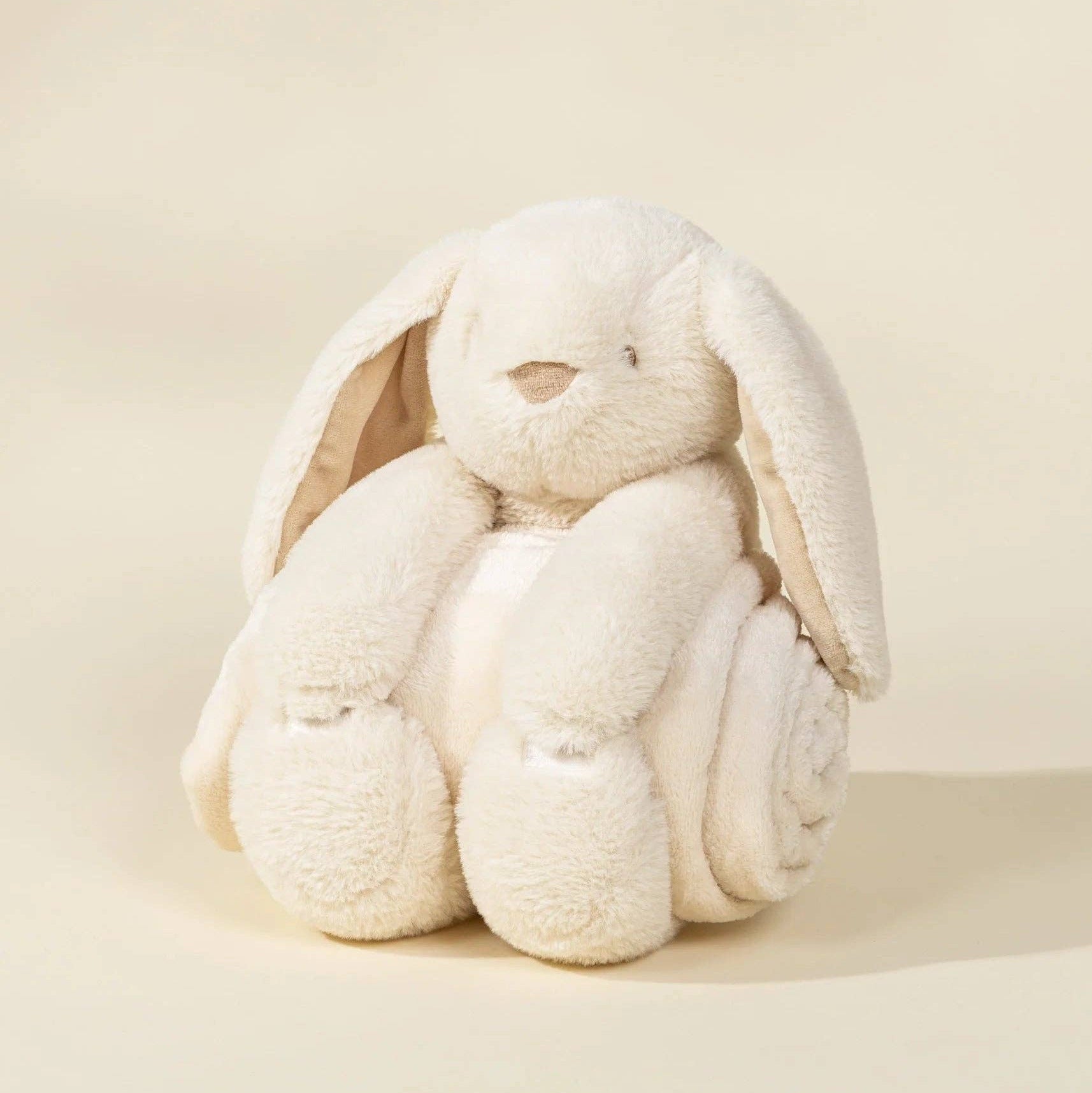 Cream-colored plush bunny toy on a beige background