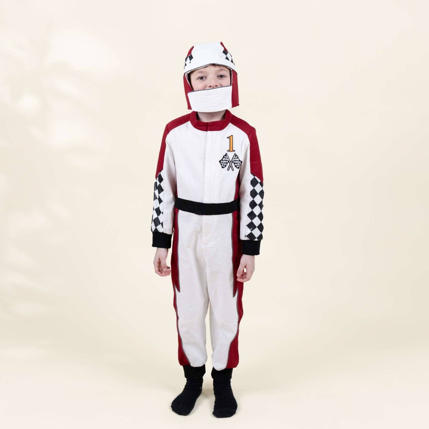 A child wearing a white, red, and black racing-inspired costume jumpsuit with a matching white helmet and face mask, standing against a plain cream studio background.