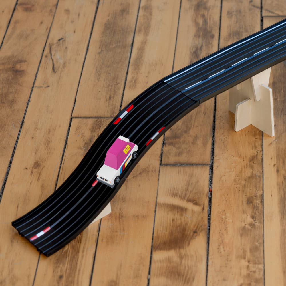 Toy car on a black track with pink top on a wooden floor