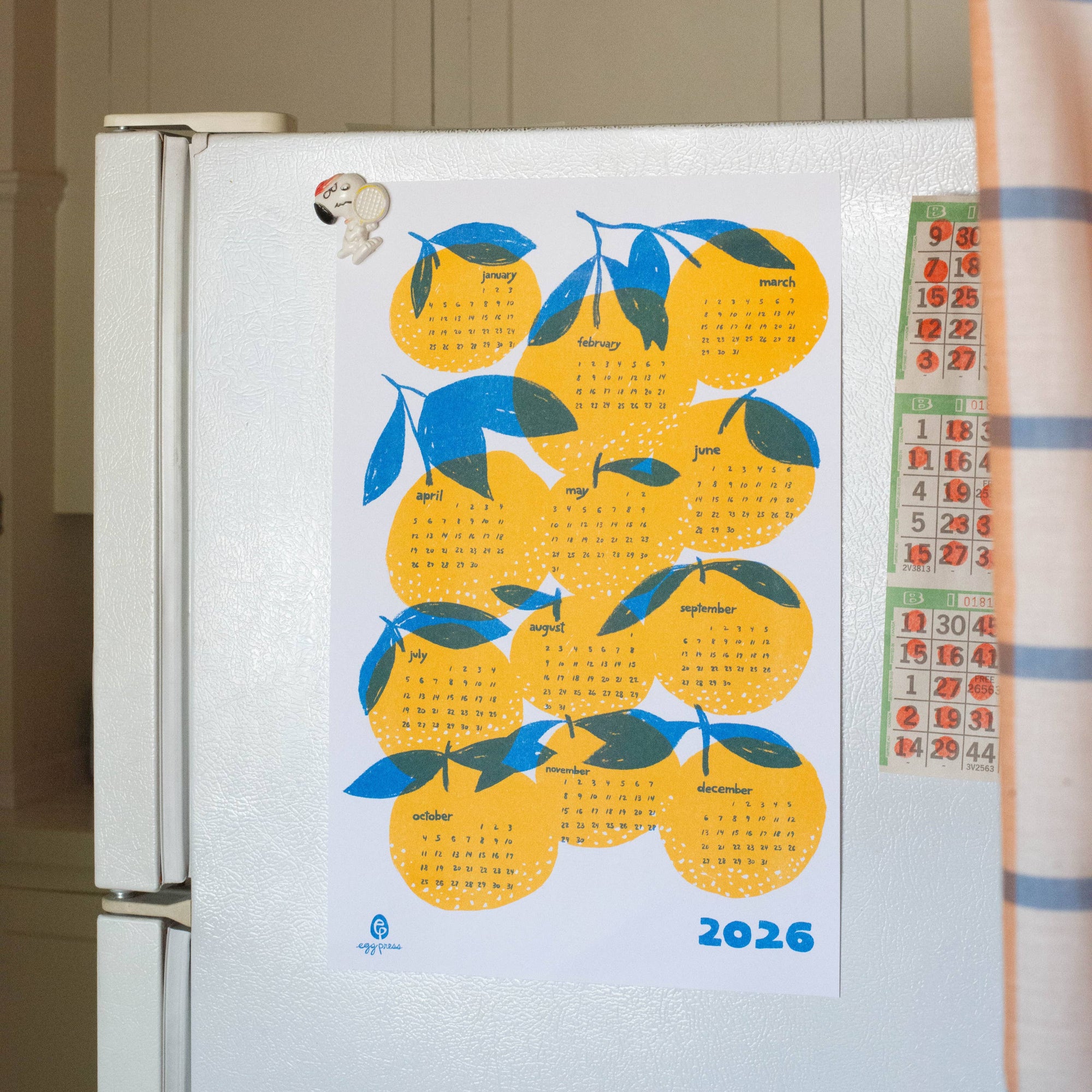 Fridge with a decorative calendar on a kitchen wall