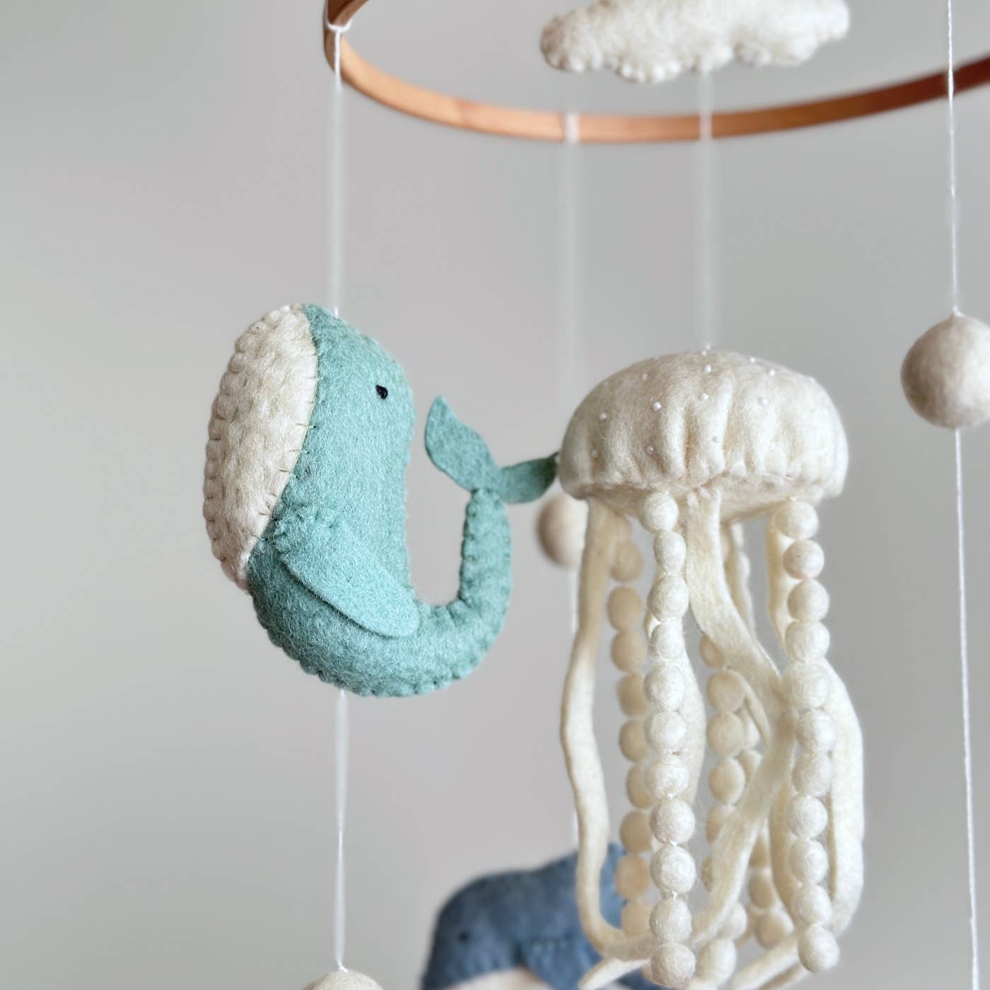 Nautical-themed mobile with whale and jellyfish decorations on a plain background