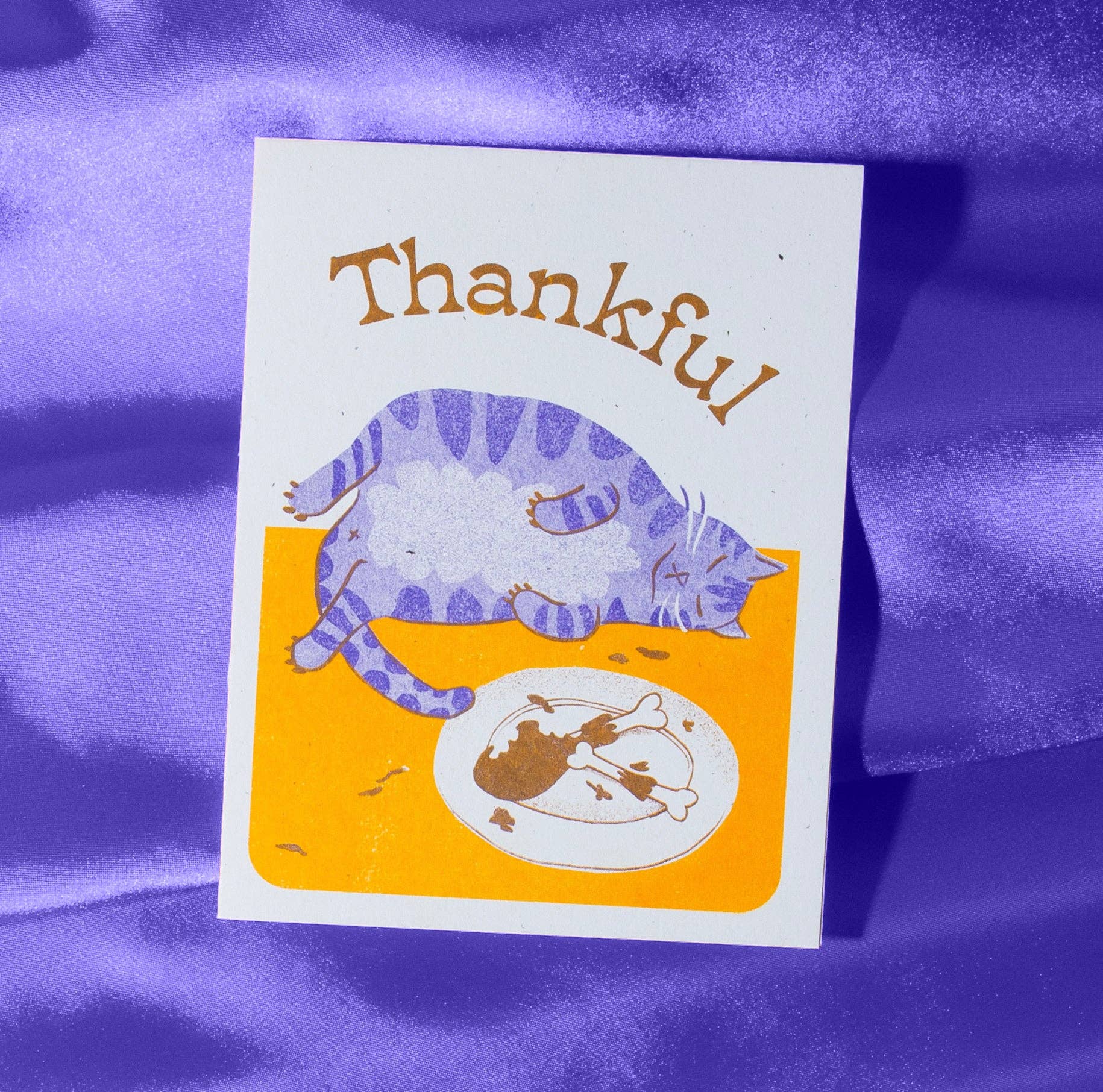 Card with a purple cat and text 'Thankful' on a purple fabric background