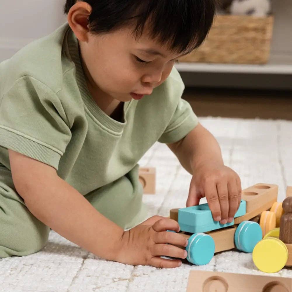 Child playing with wooden toys on a light-colored rug