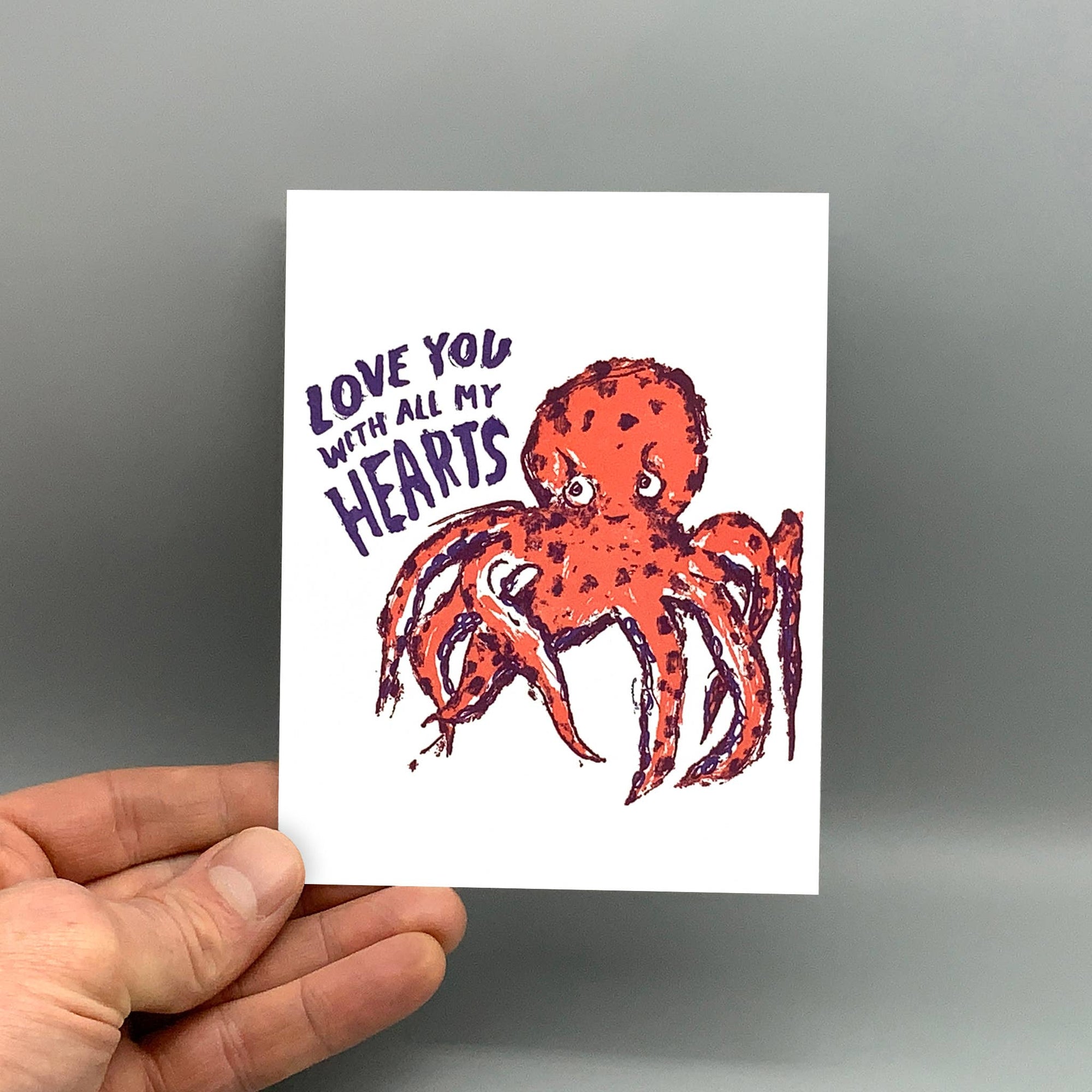 Card with an octopus illustration and text held by a hand against a gray background