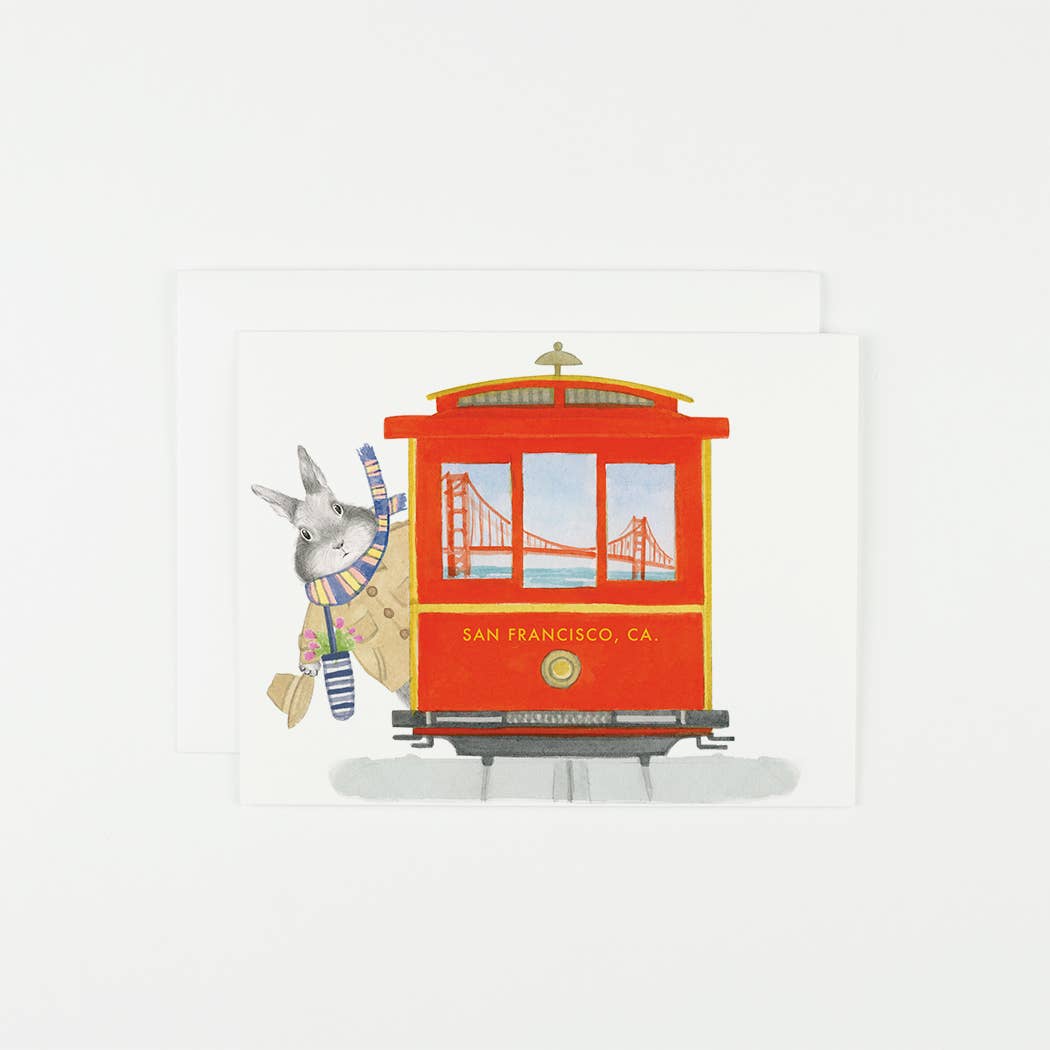 Illustration of a red cable car with a donkey character and the Golden Gate Bridge in the background on a white card.