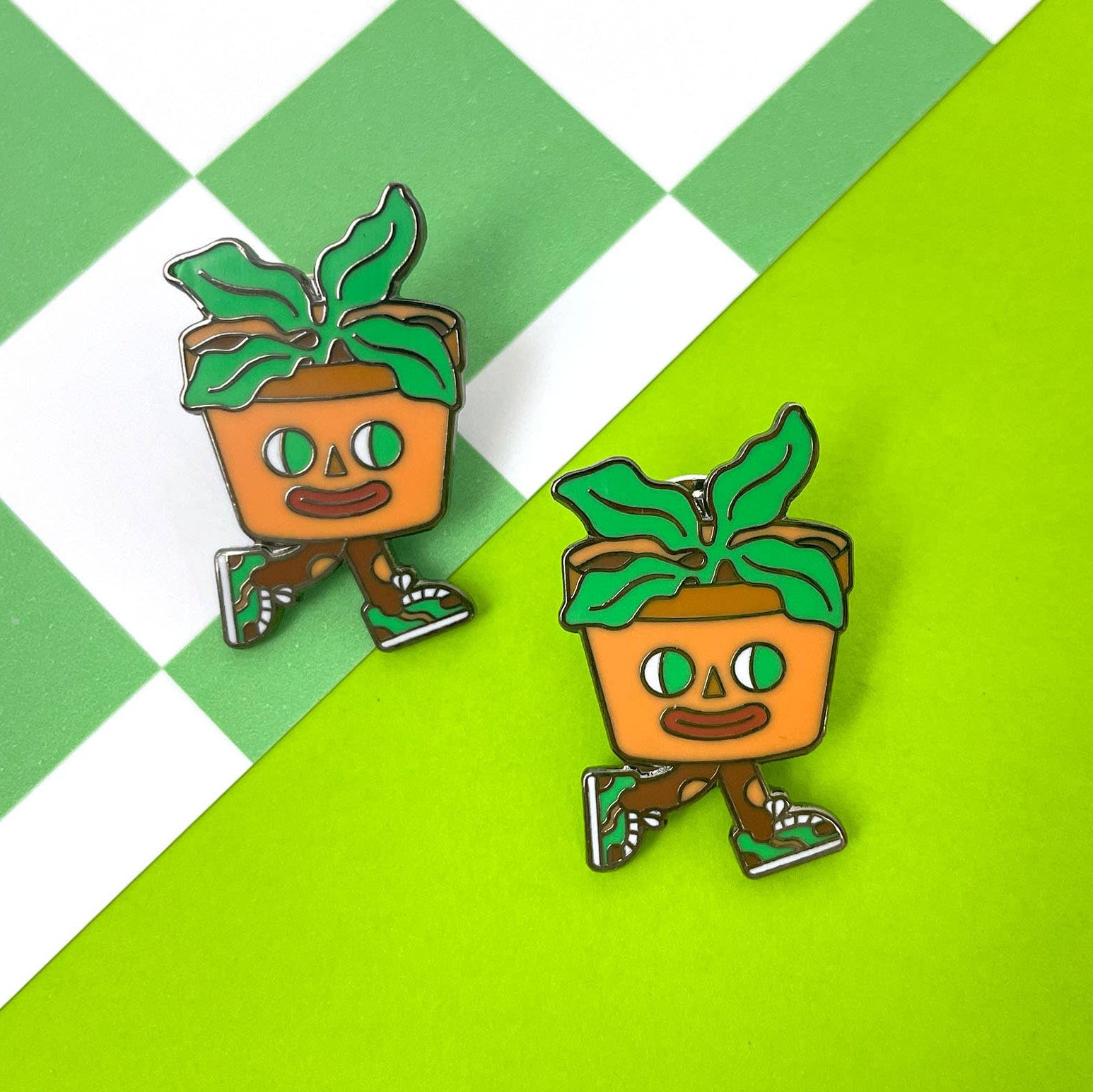 Two cartoon-style potted plant pins on a green and white checkered background