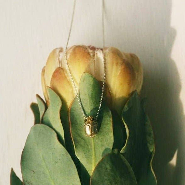 Gold necklace with a pendant on a leaf against a white background