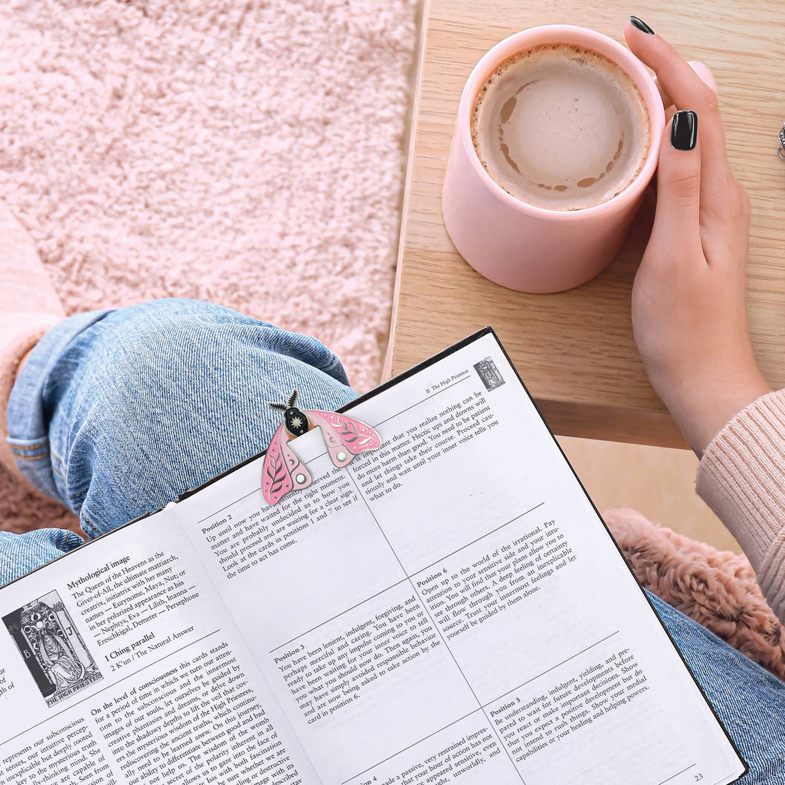 Person reading a book with a cup of coffee on a wooden table