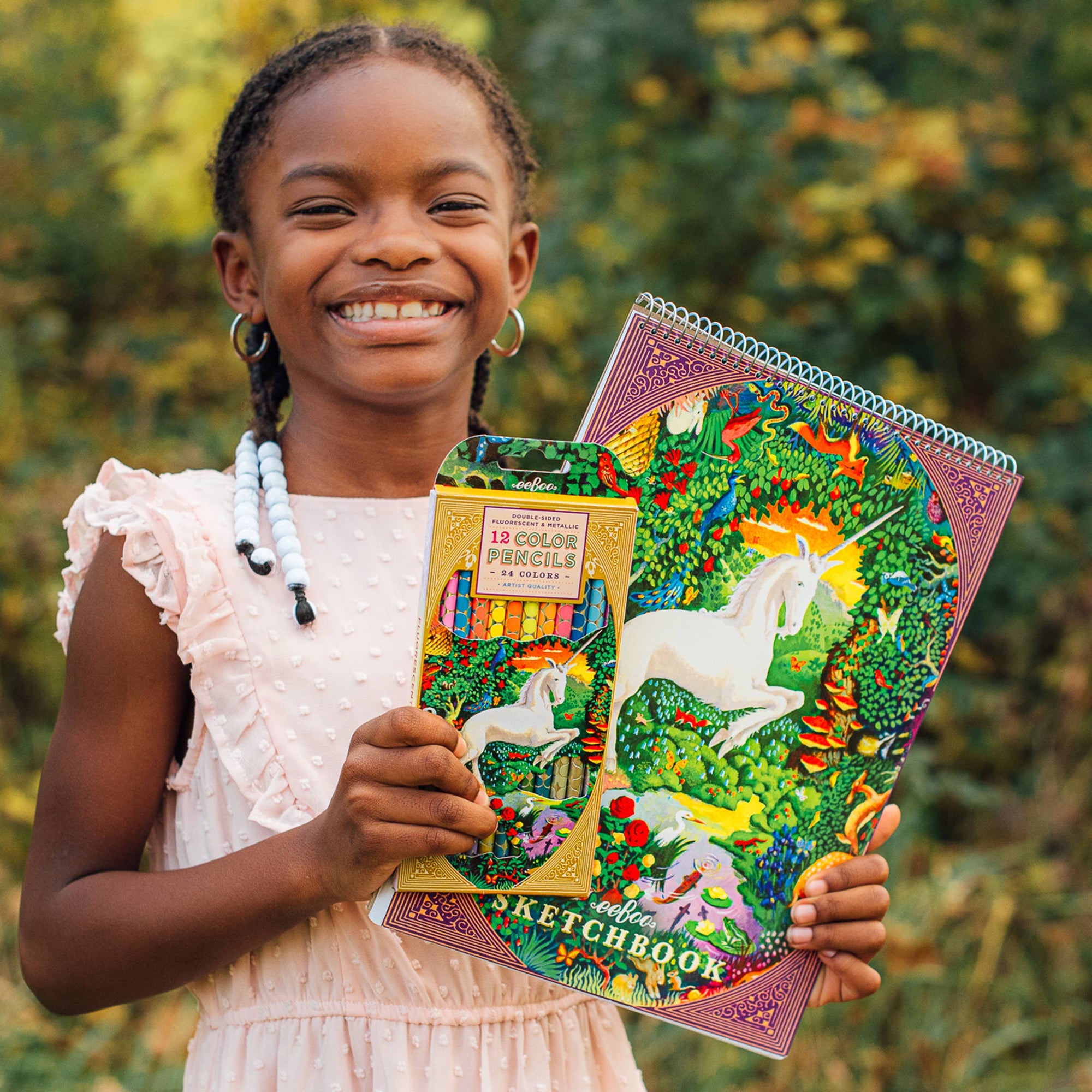 Young girl holding a colorful notebook with unicorn design and a pencil case.