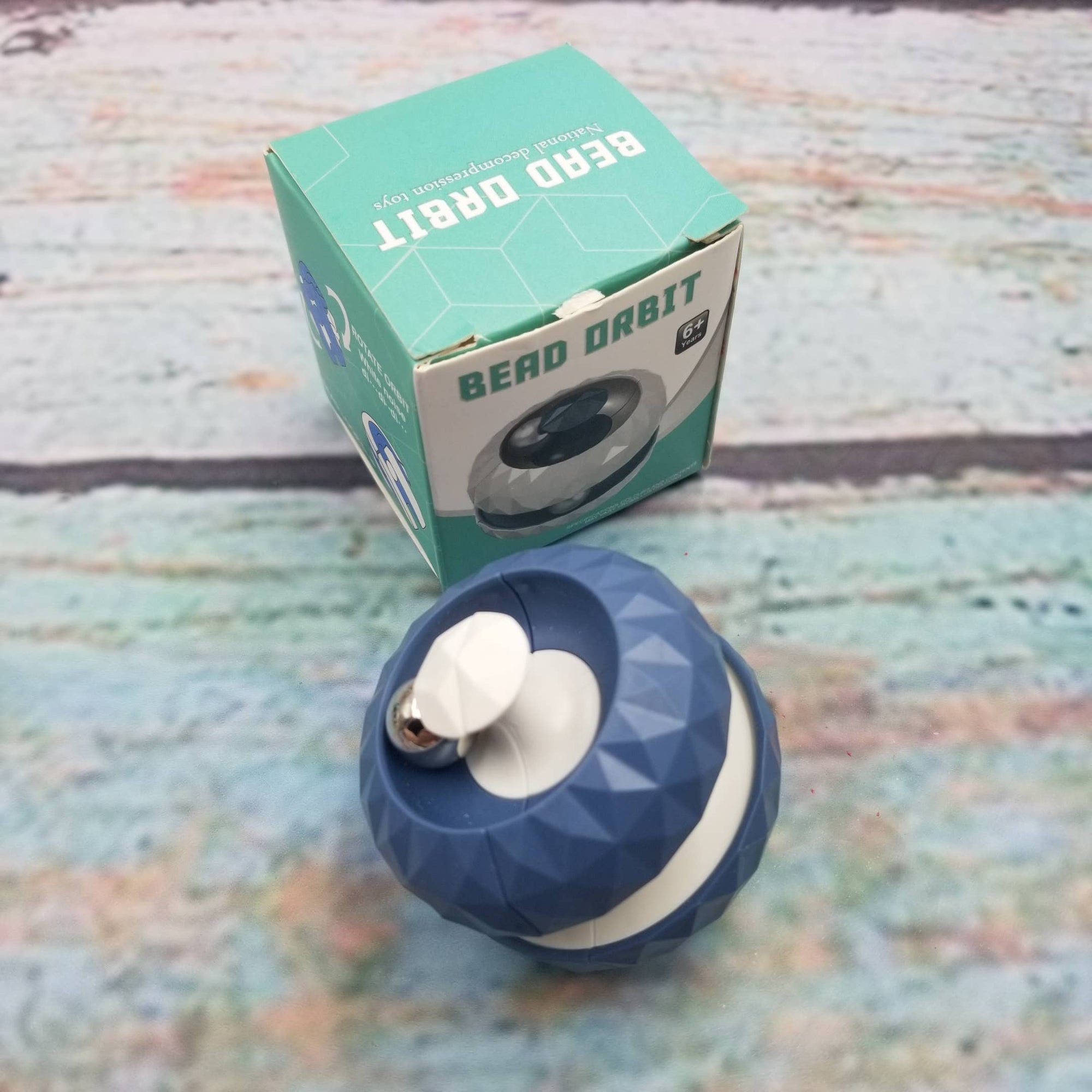 Blue and white geometric object with 'Bero Orbit' packaging on a textured surface