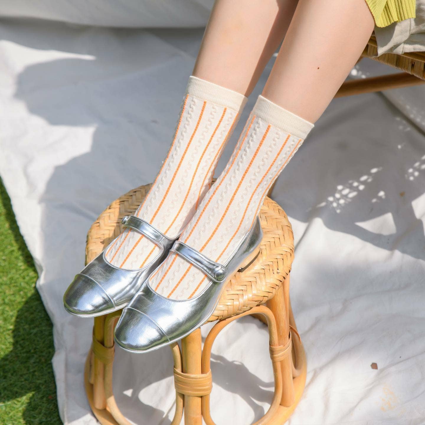 Person wearing striped socks and silver shoes on a wicker chair outdoors.