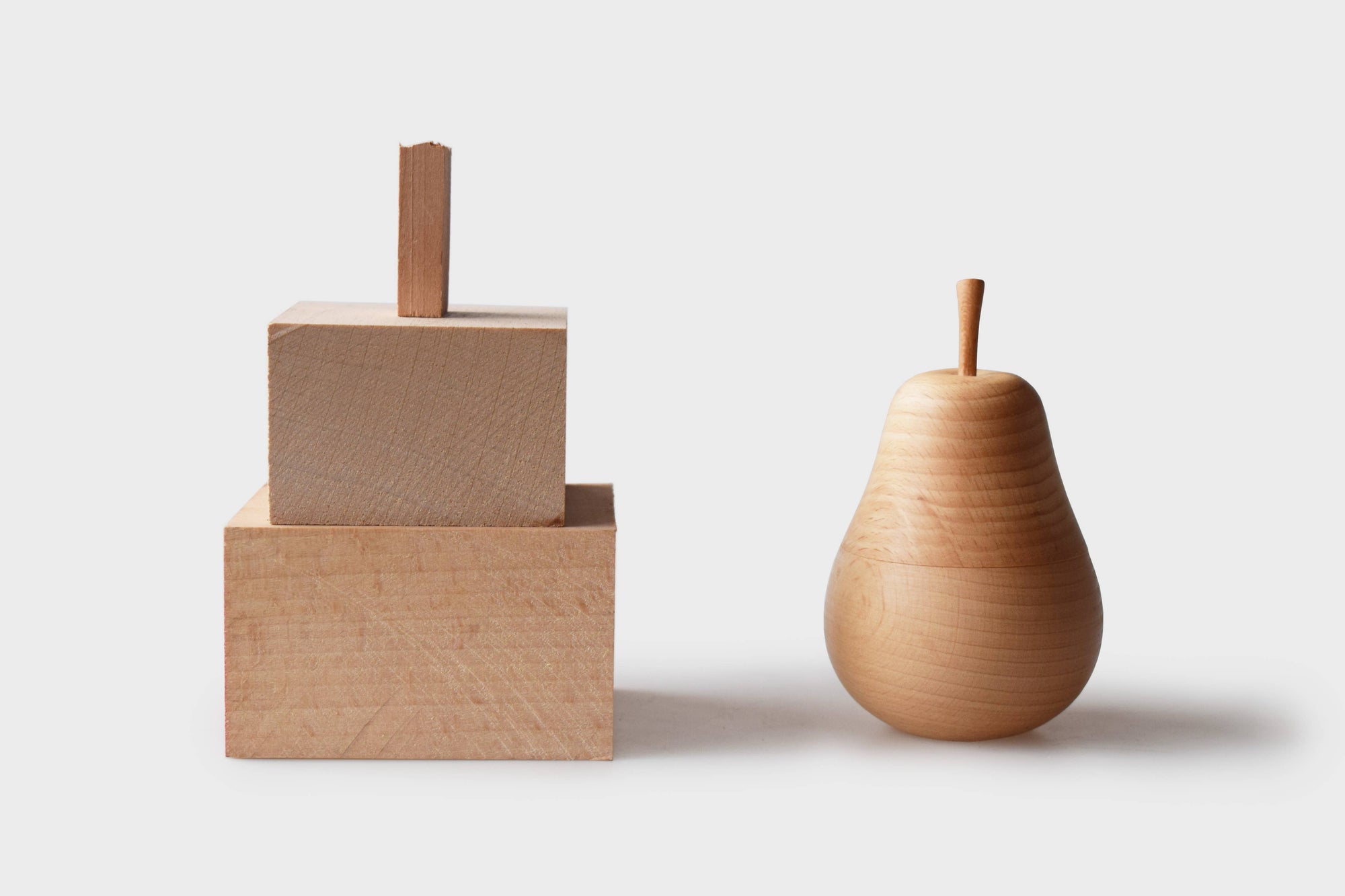 Two wooden objects resembling a block and a pear on a light background