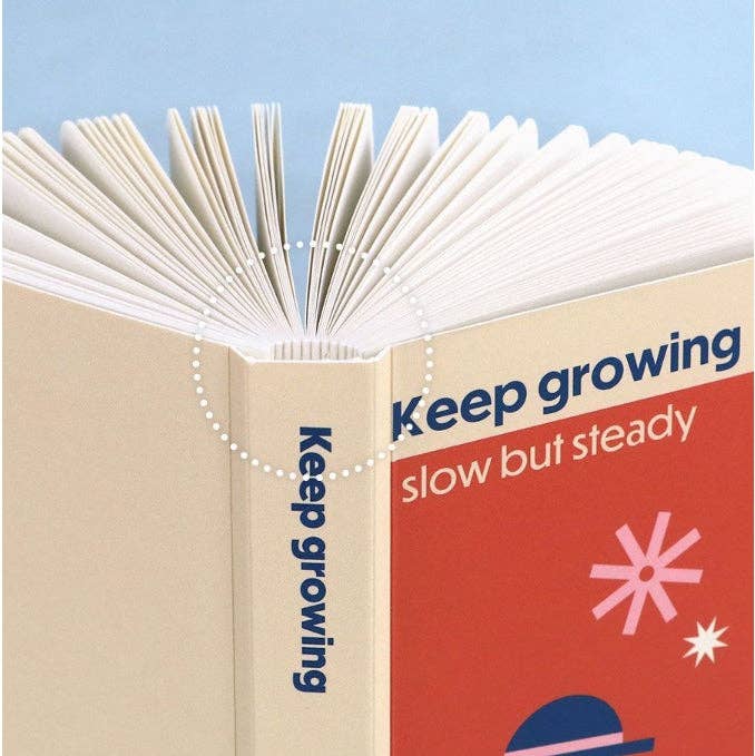 Open book with motivational text 'Keep growing, slow but steady' on a blue background