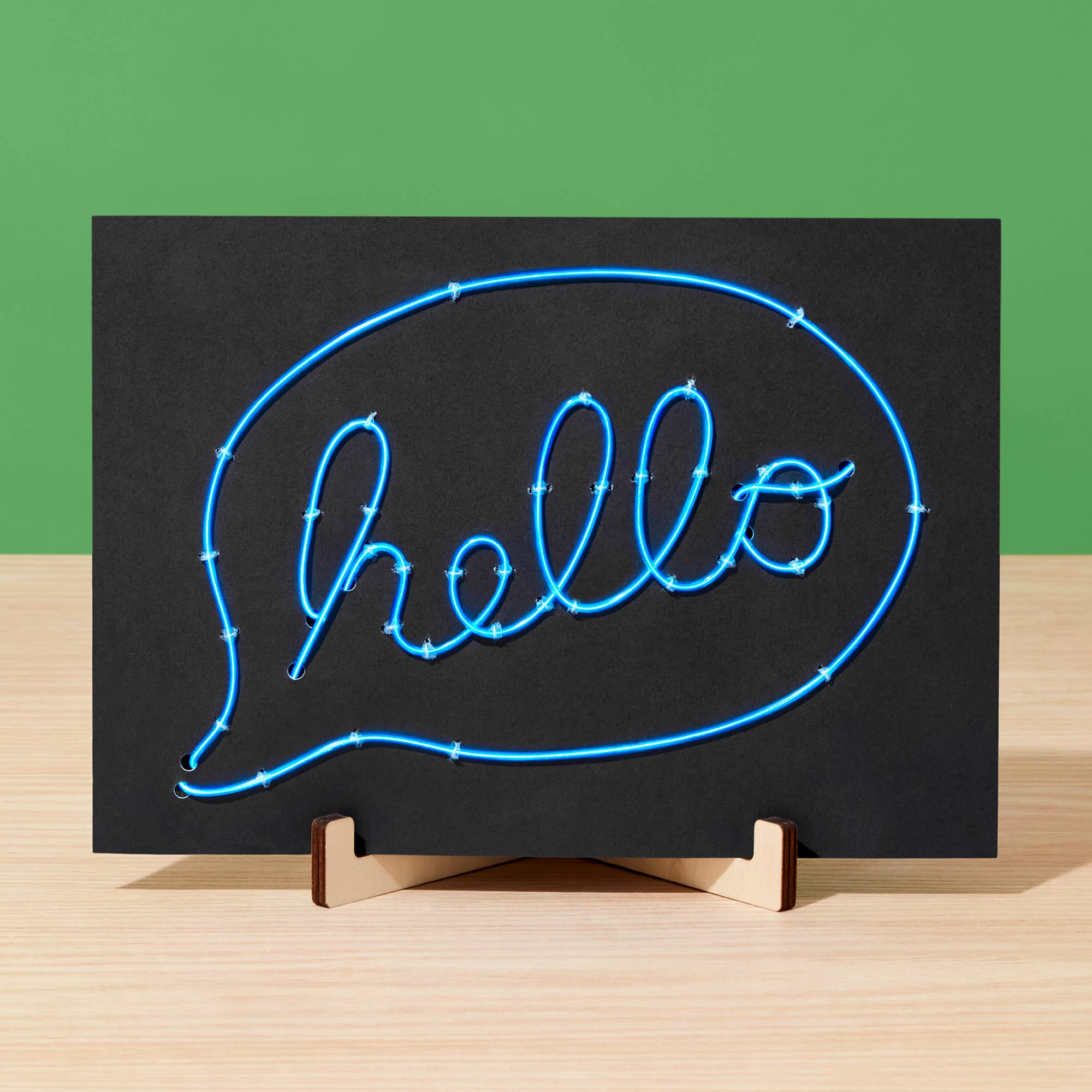 Neon sign with 'hello' in a speech bubble on a black background