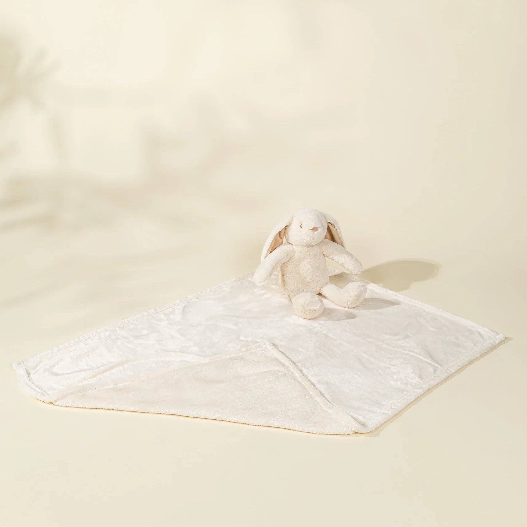 White plush bunny toy on a white blanket with a plain background
