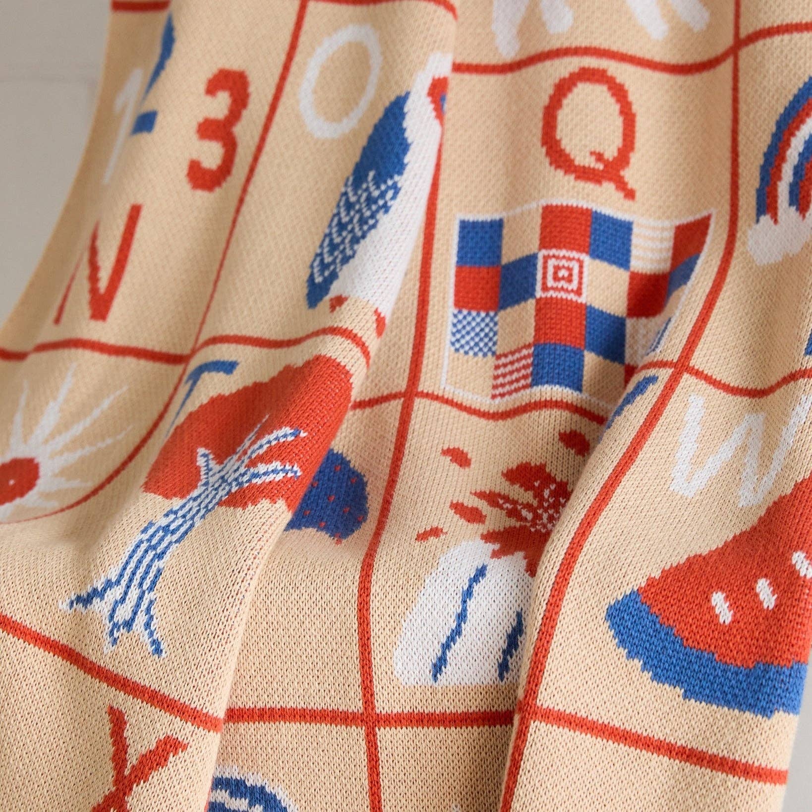 Close-up of fabric with colorful patterns including numbers, letters, and abstract shapes on a beige background.