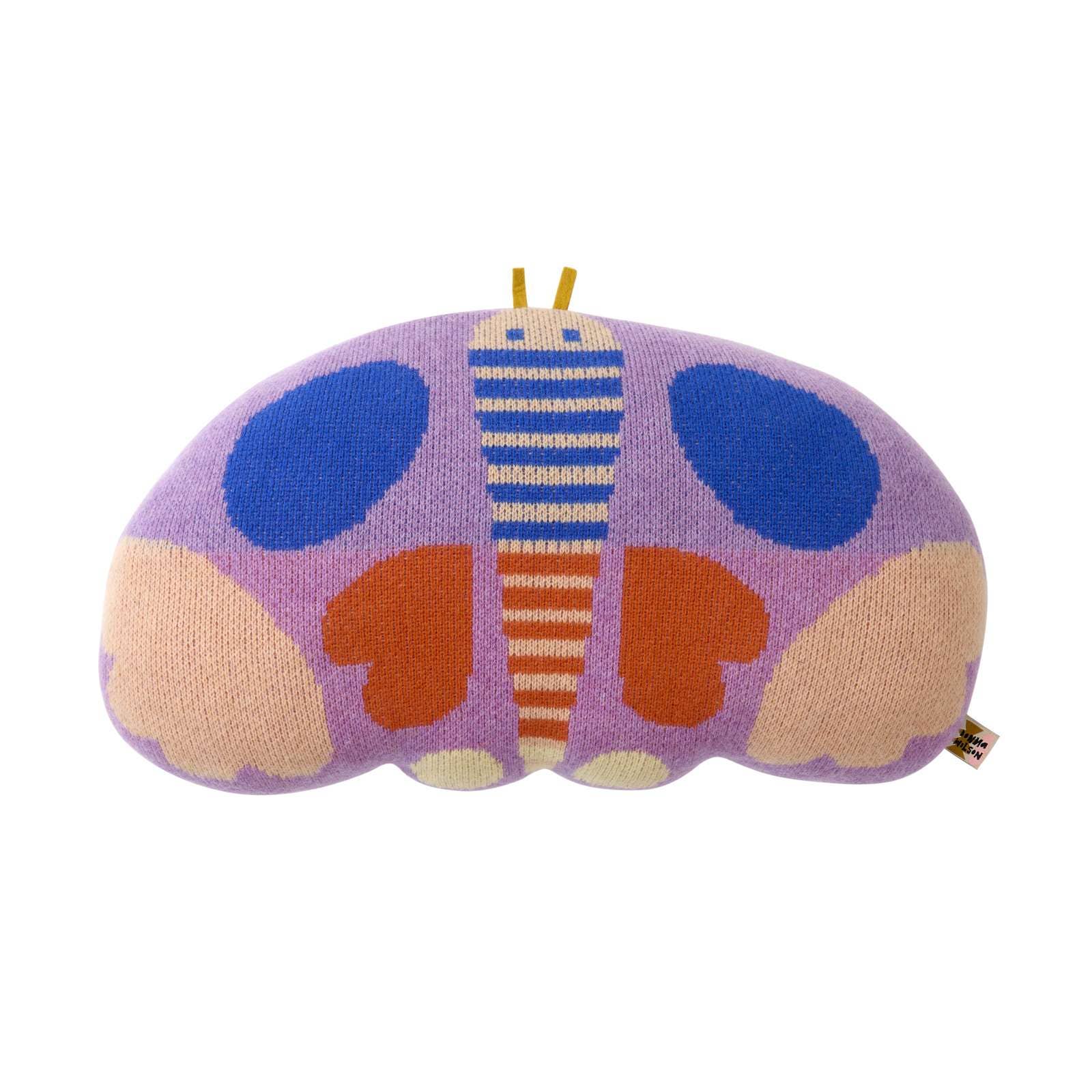 A knitted butterfly-shaped pillow in pastel purple, blue, orange, and beige, photographed on a solid white background.