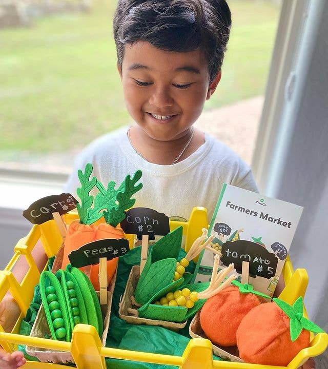 Child playing with a toy vegetable stand outdoors