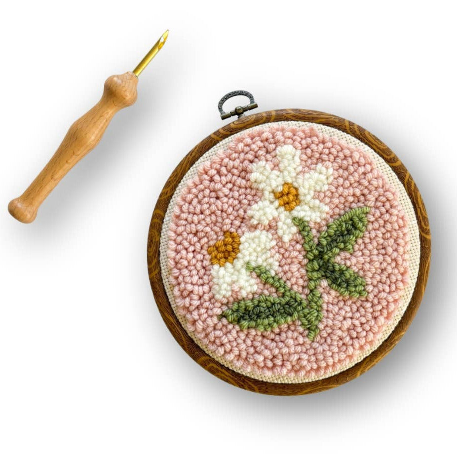 Embroidery hoop with floral design and pink bead border on a white background