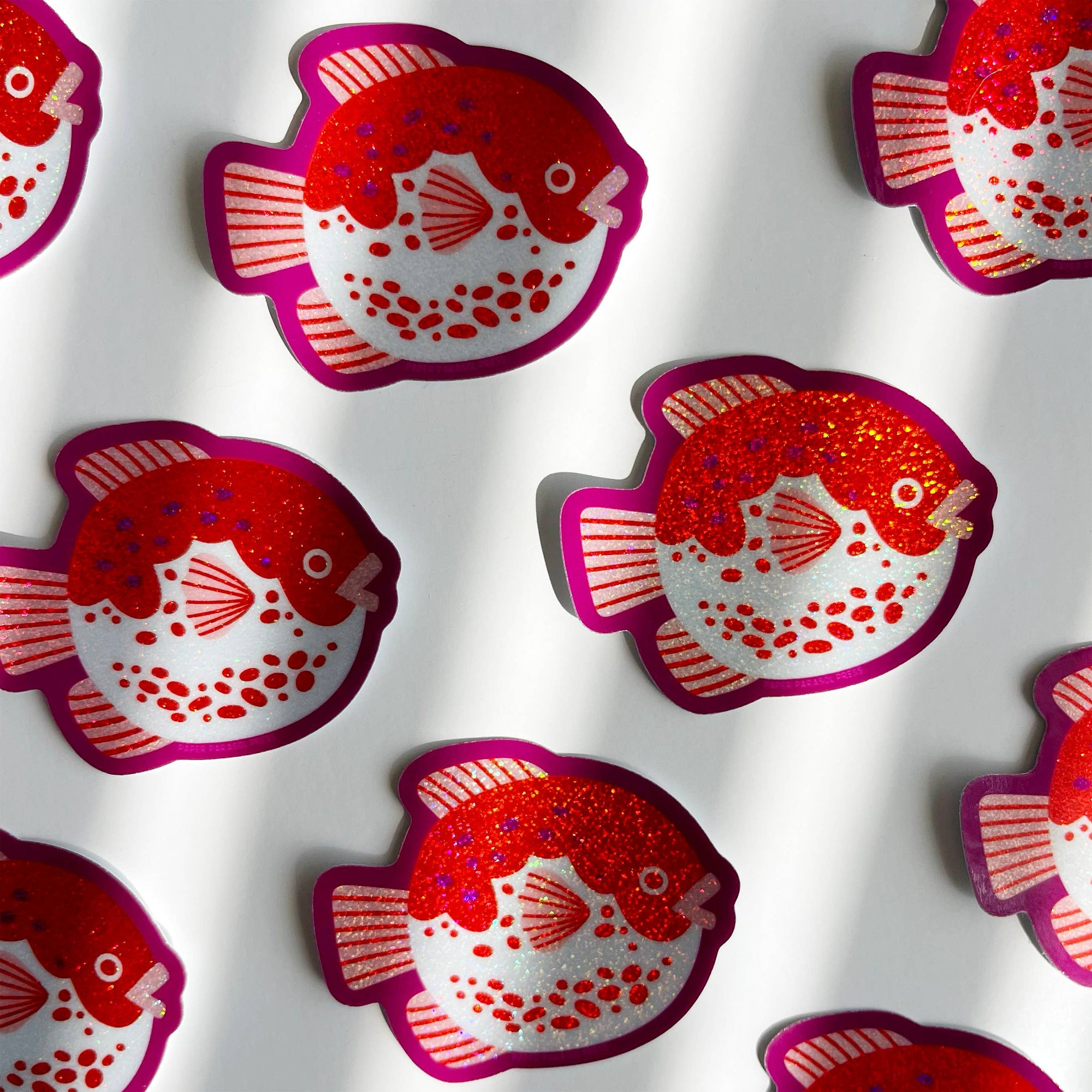 Pattern of red and pink fish-shaped stickers on a white background