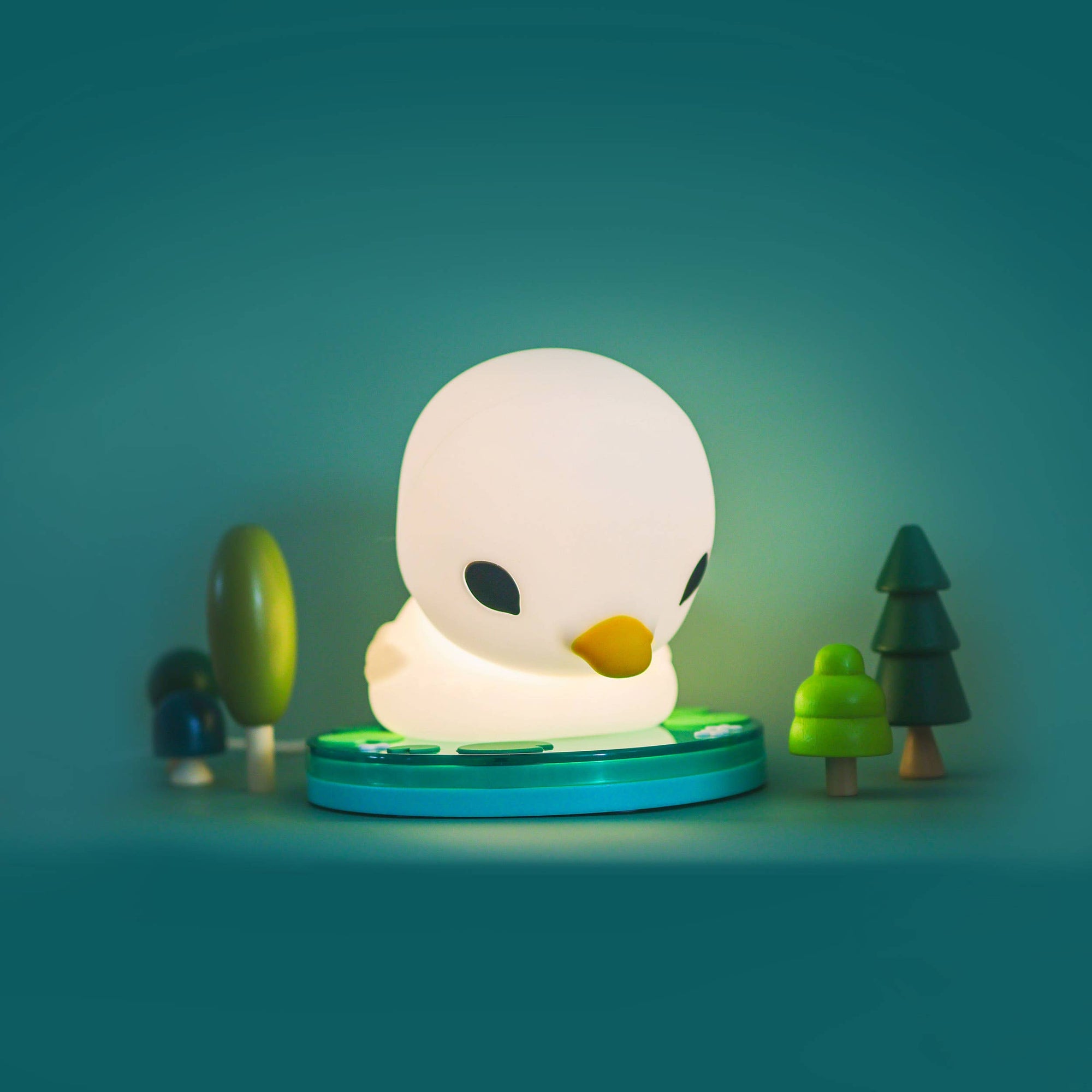 White duck-shaped night light with a green base on a teal background