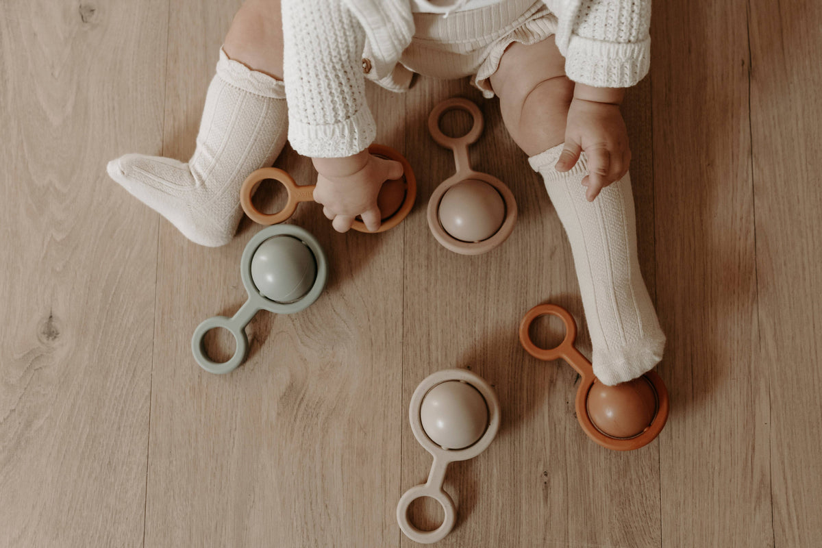 Baby playing with colorful wooden toys on a wooden floor