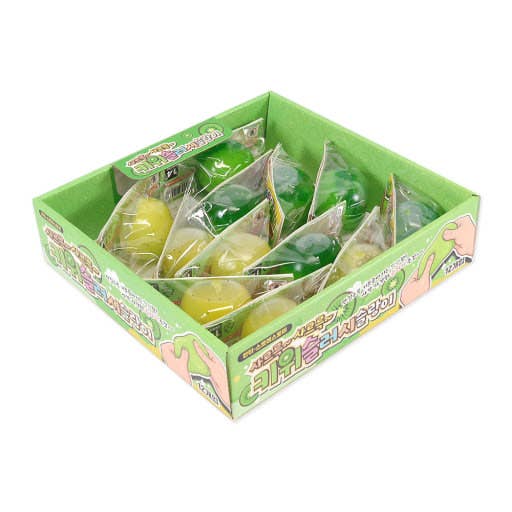 A green cardboard display box filled with individually wrapped round candies in yellow and green, photographed on a plain white background.