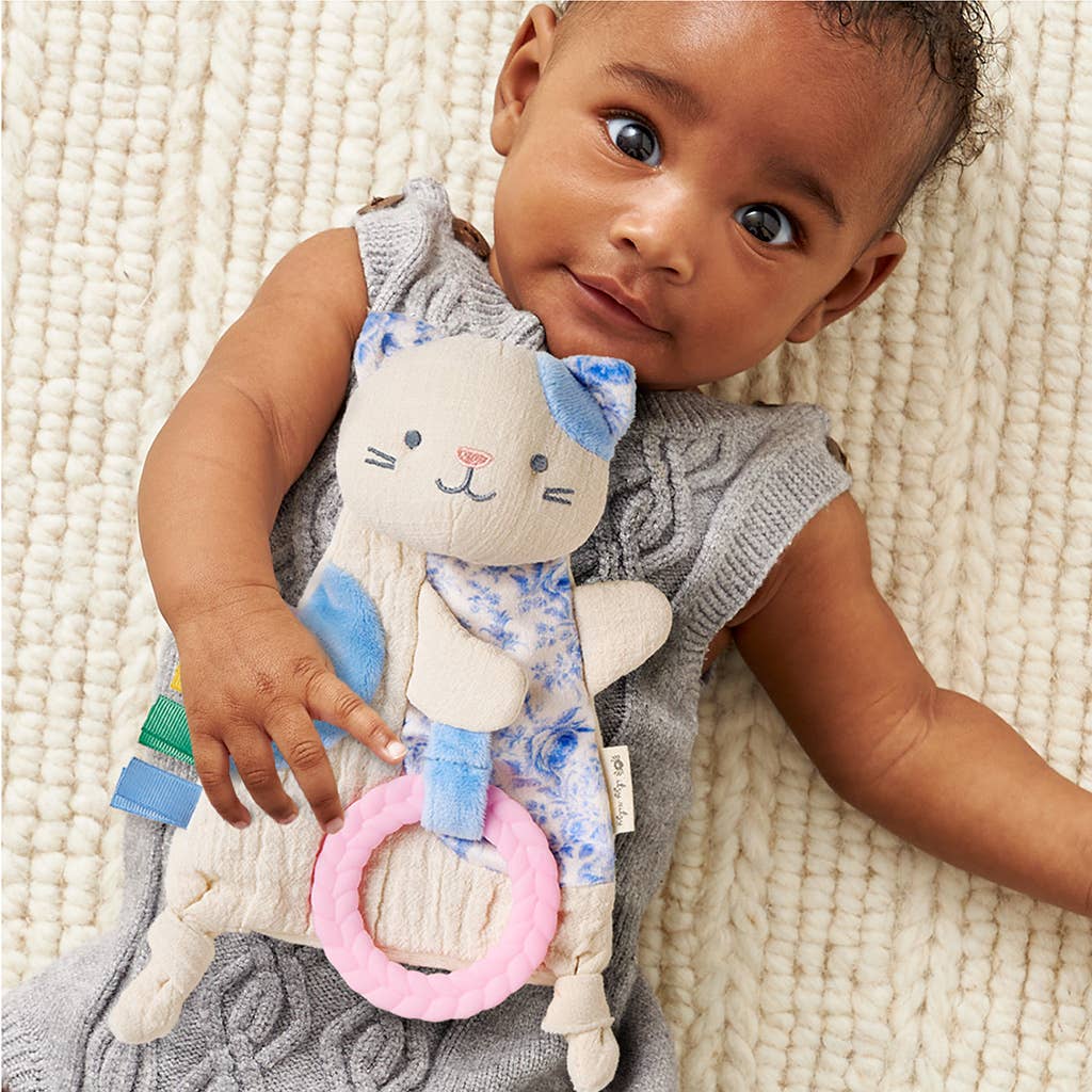 Baby holding a soft toy with cat design on a textured surface