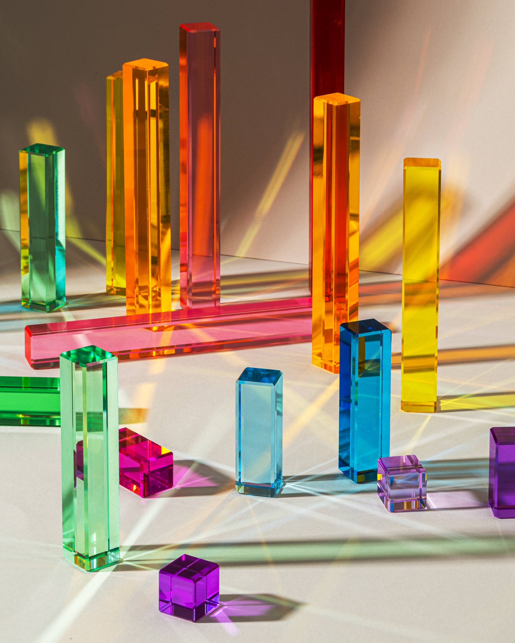 Colorful transparent geometric blocks on a reflective surface with light reflections.