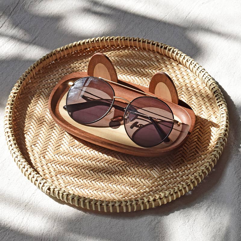 Sunglasses in a bear-shaped sunglasses case on a woven tray