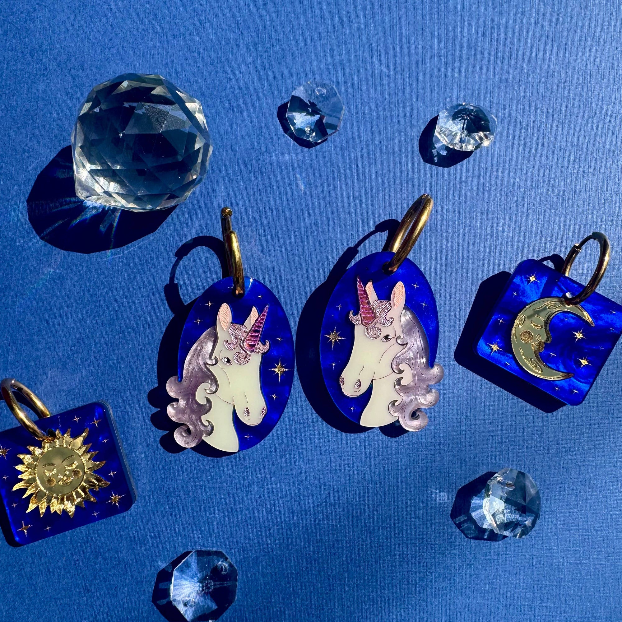Decorative earrings with unicorn designs on a blue background