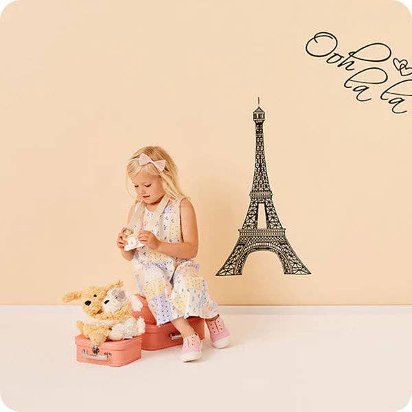 Child with a toy near a small Eiffel Tower model on a beige background
