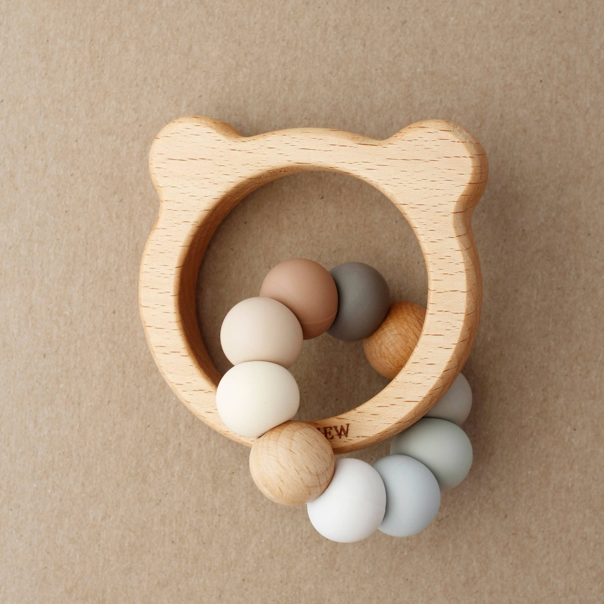 Wooden teething ring with colorful beads on a beige background