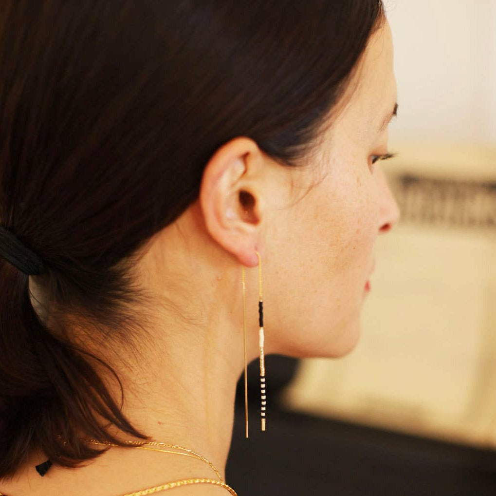 Woman wearing a long gold earring with a blurred background
