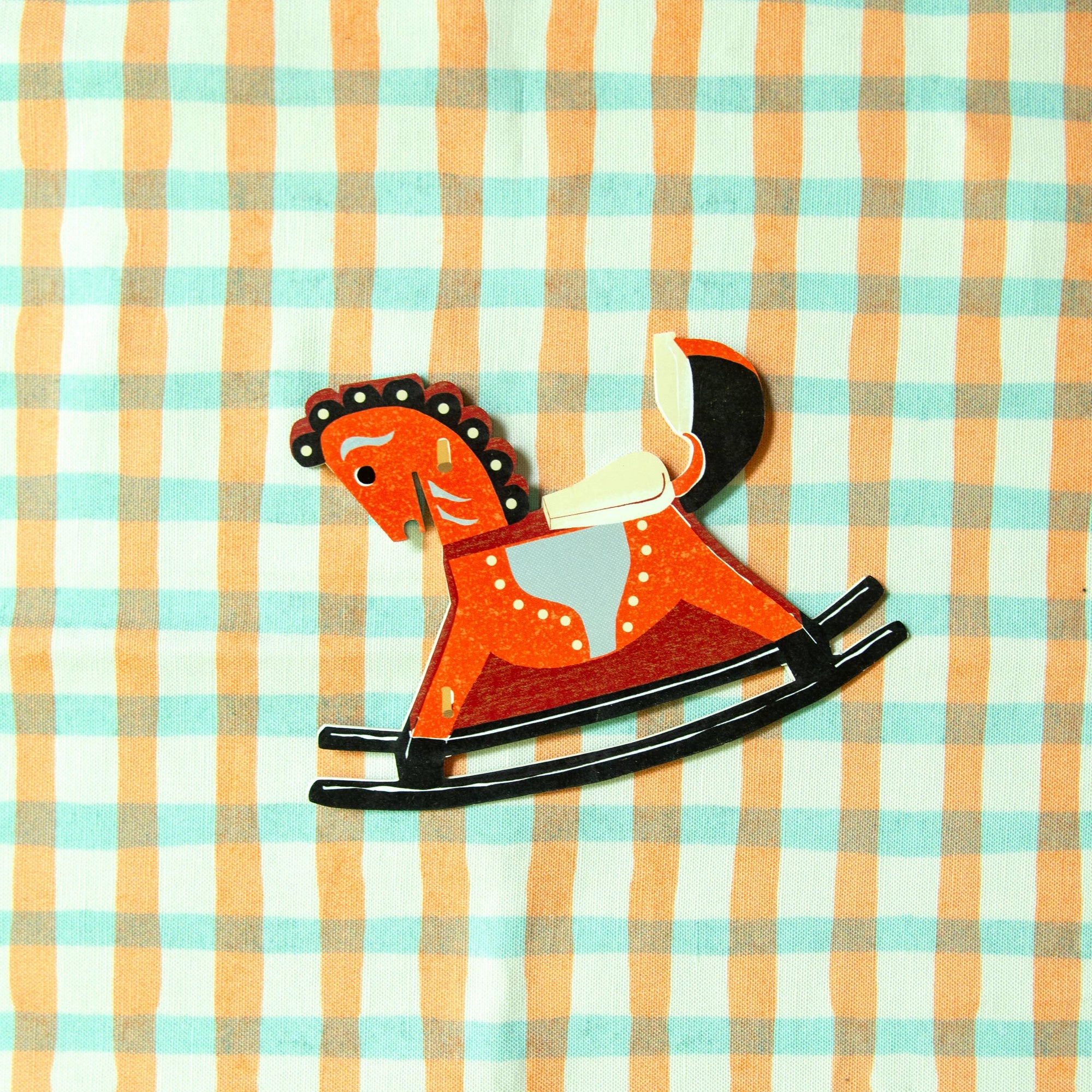 Rustic wooden rocking horse toy on a checkered fabric background