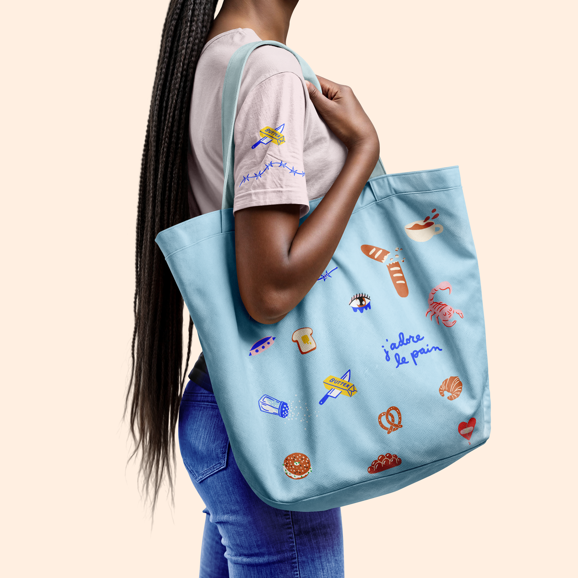 Person holding a light blue tote bag with colorful designs on a beige background