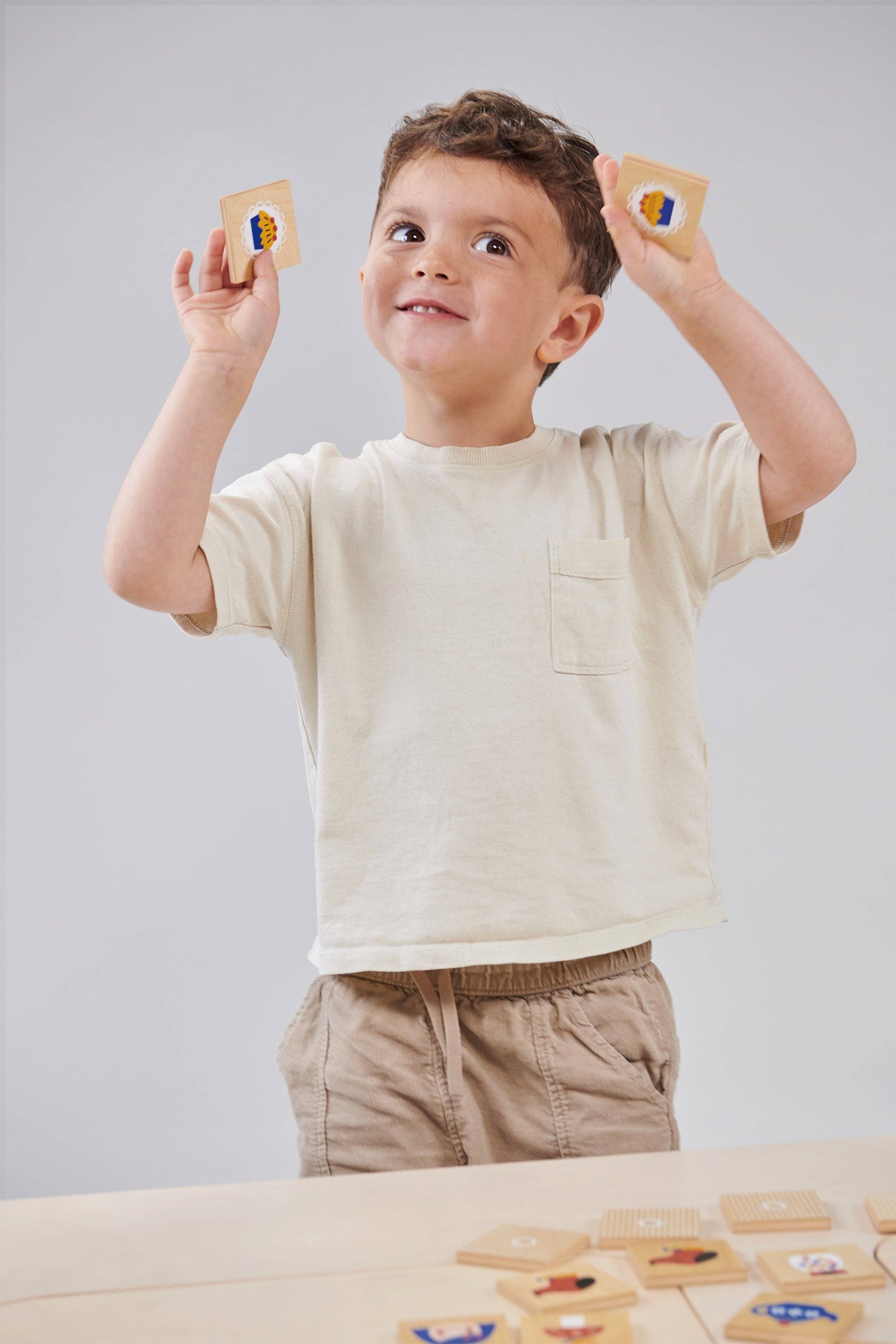 Child holding up educational cards with colorful symbols against a plain background